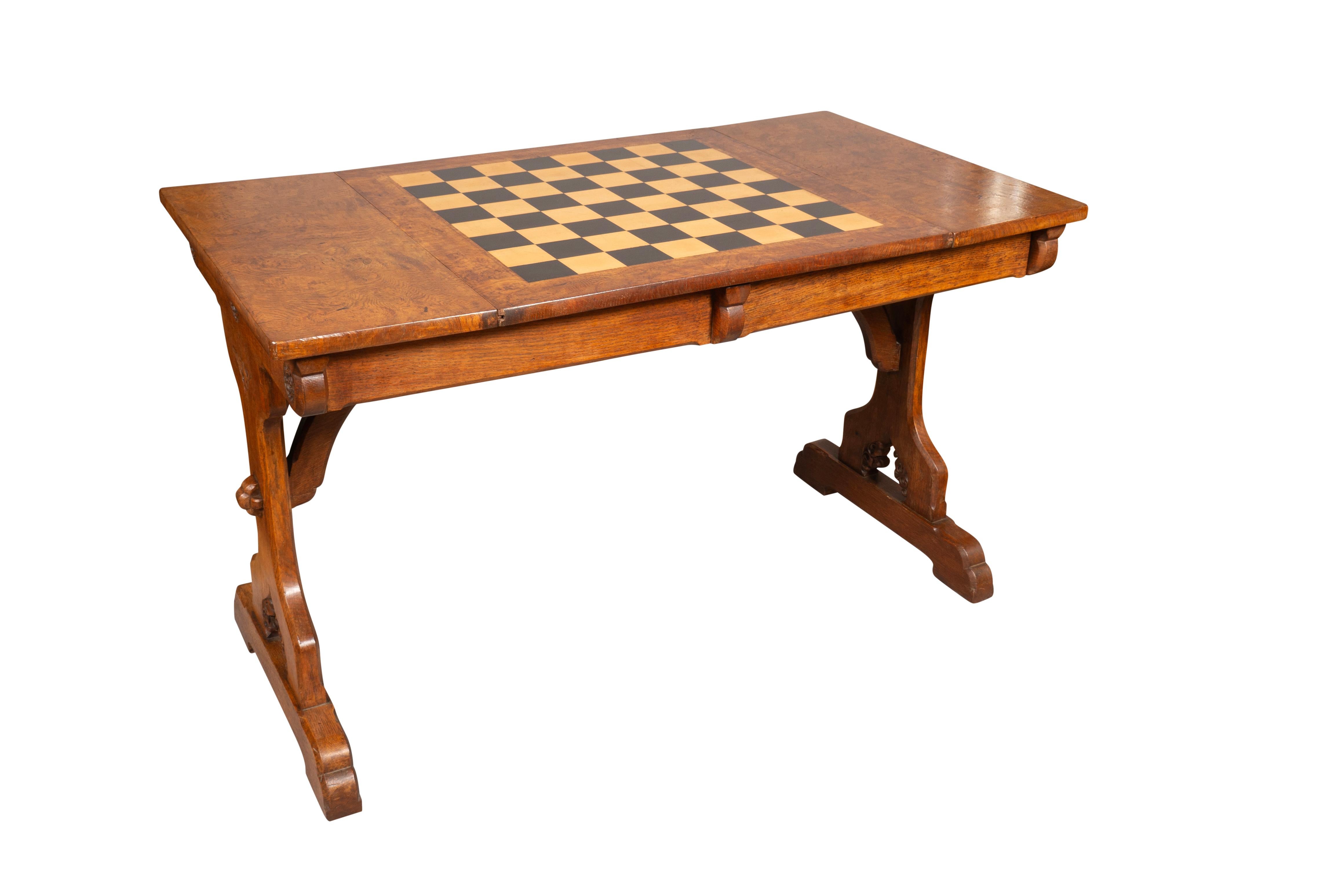 Rectangular with pollard oak veneer top with central reversible game board. The frieze containing two drawers. The ends of the table with carved Tudor rose decoration. Trestle base with carved inscription of two families initials possibly a wedding