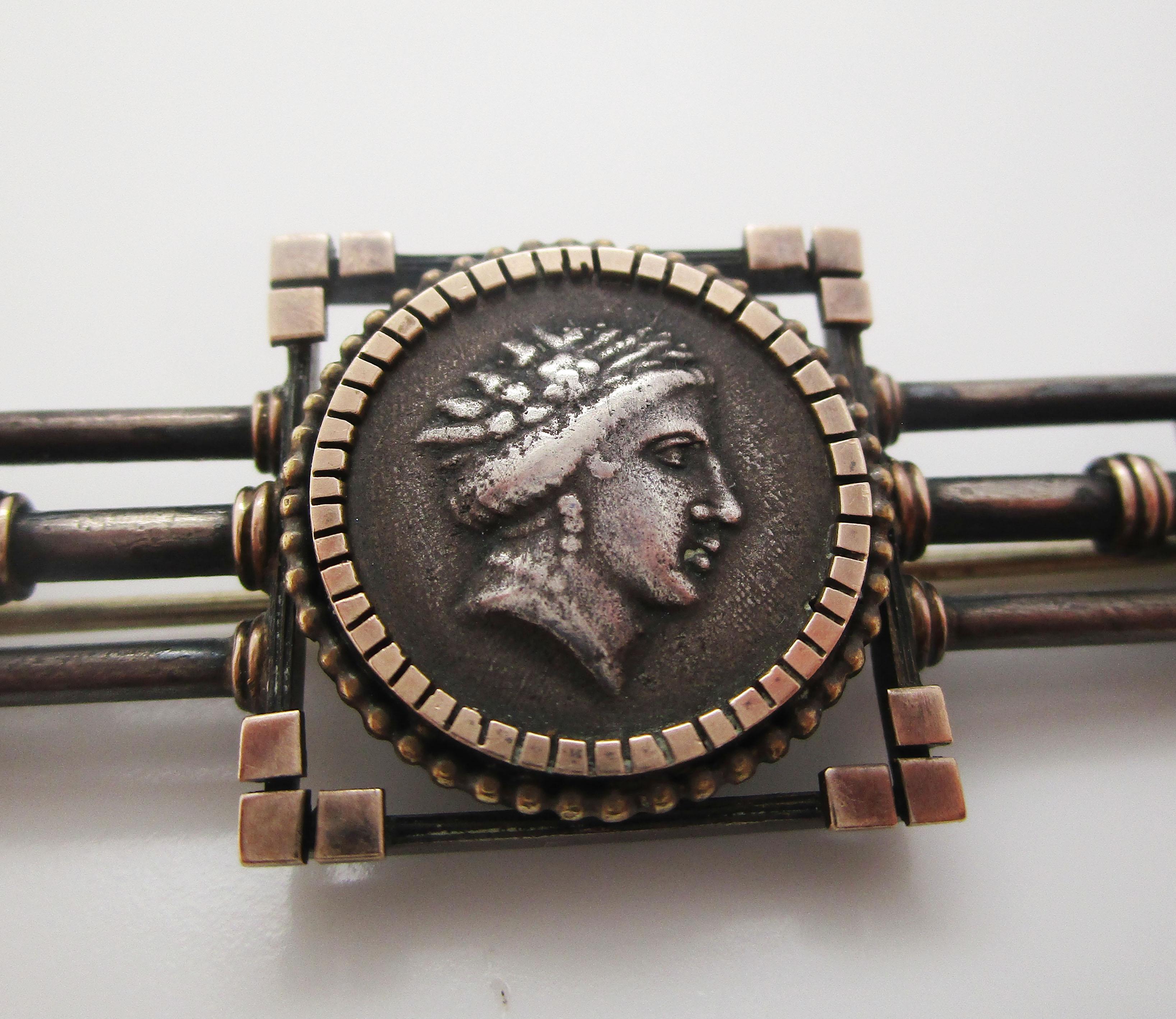 This awesome Victorian pin is in sterling silver and features a Roman-style Homeric medallion at its center, accented by a dramatic bar layout. The medallion at the center bears the Classical style face of a man and is framed by a geometric layout