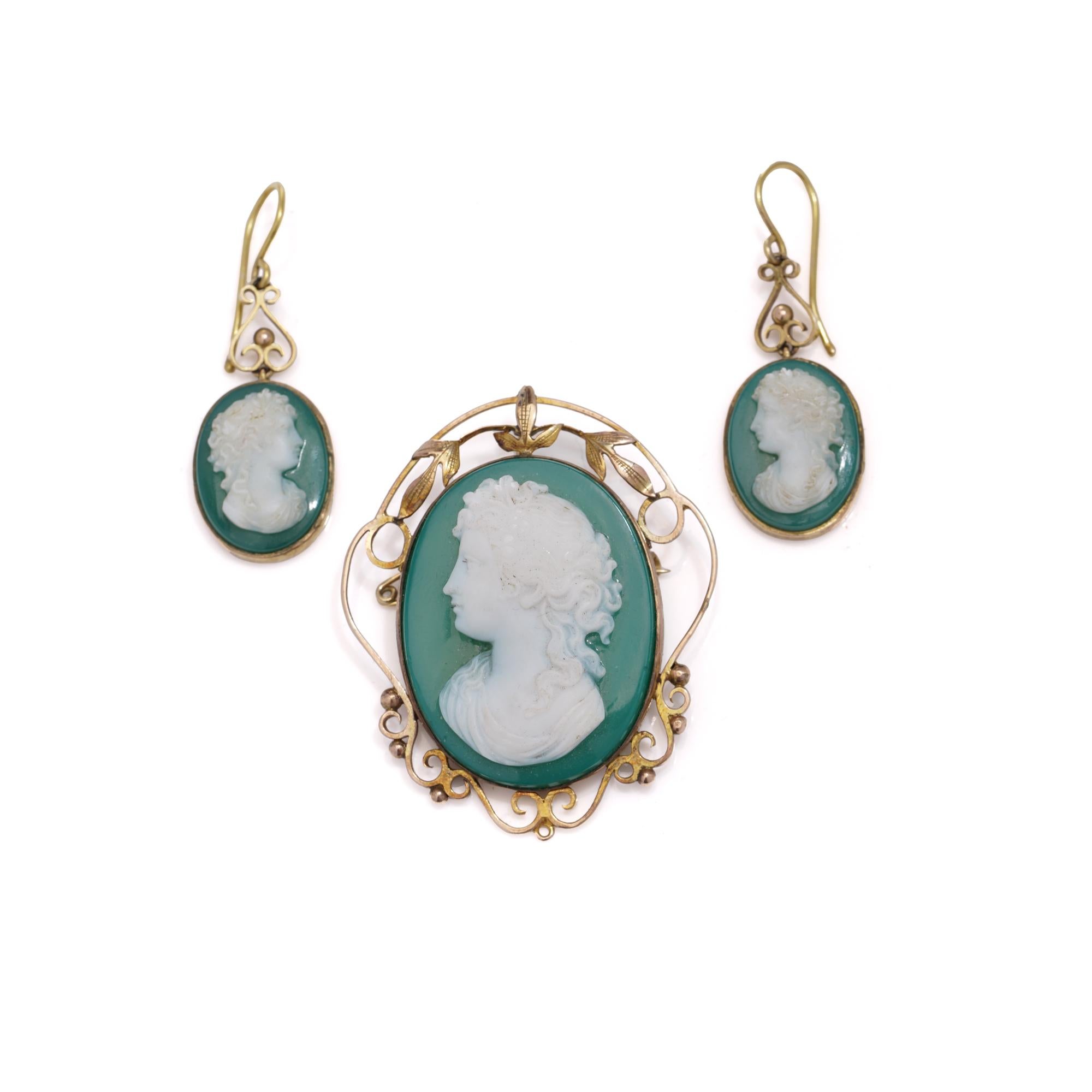 Antique Victorian suite crafted in 9kt yellow gold featuring green and white agate. Includes a brooch depicting a lady in profile adorned with an ivy garland, along with earrings portraying women facing left and right with braided hair.
Comes with