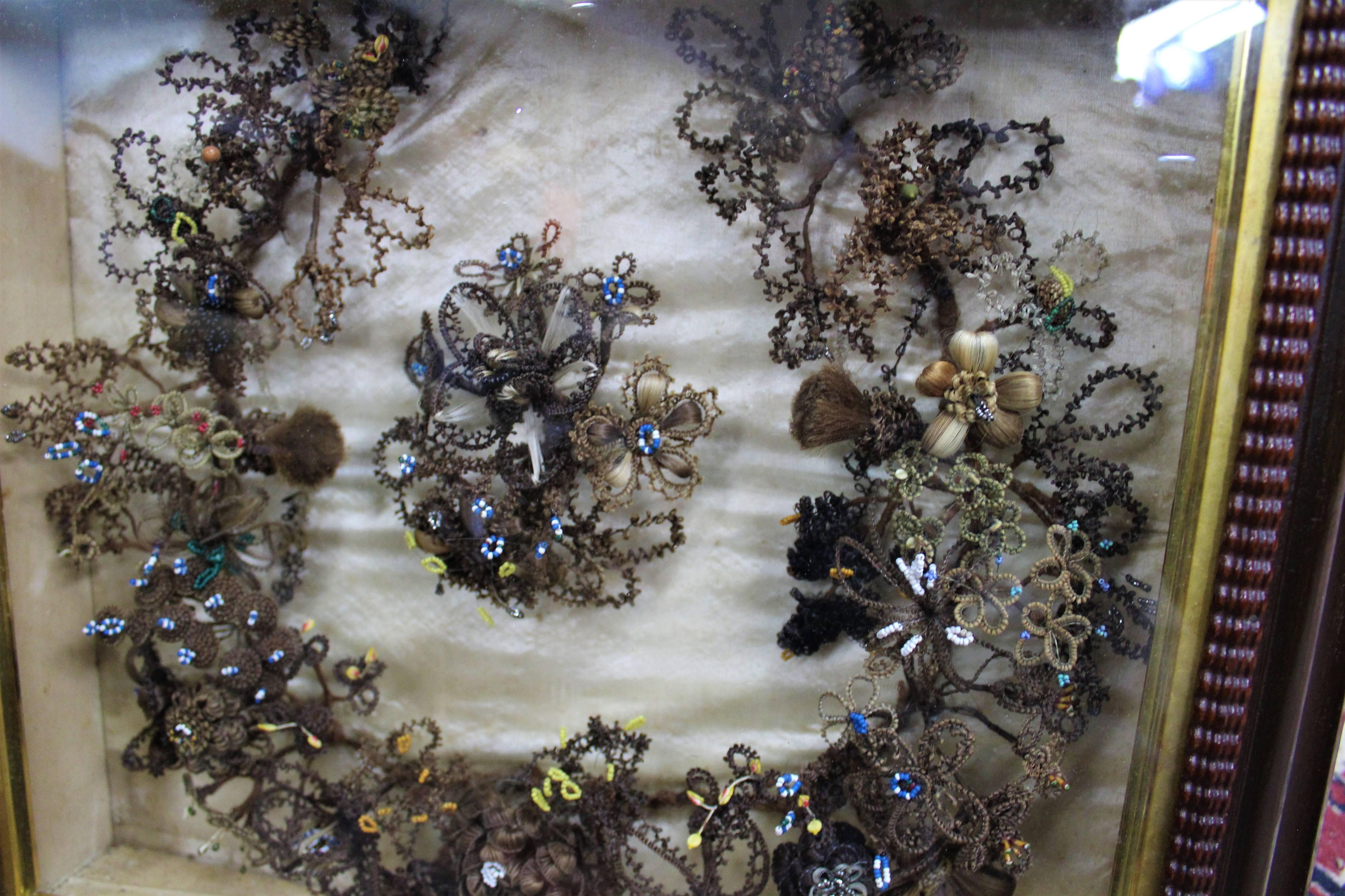 Cette couronne de cheveux de deuil complexe:: datant de 1860:: est tissée avec des cheveux humains de différentes couleurs et des perles de verre de différentes couleurs mélangées aux cheveux.  Encadré dans un beau cadre ancien avec verre. 

Une