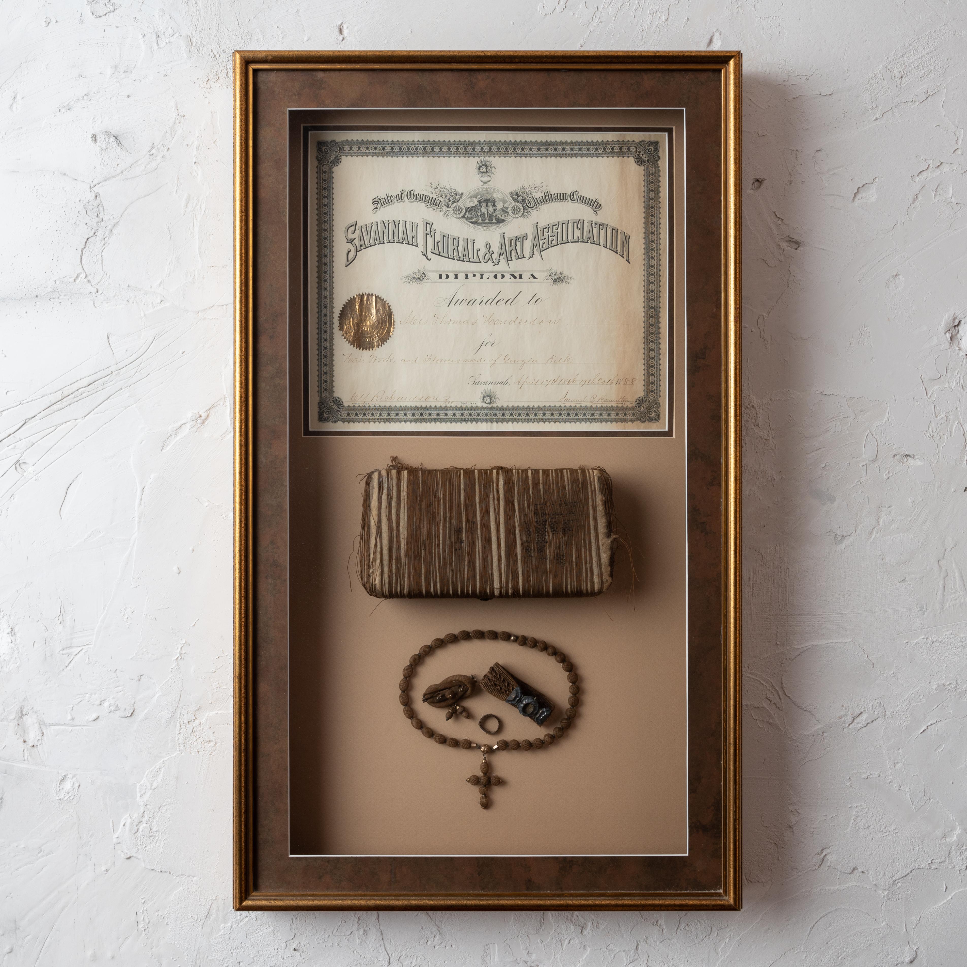 A set of hair-work articles and award lithograph associated with the Flower Show of Savannah, Georgia, 1888.  Not removed for inspection, but likely sterling and gold.  Presented in deep shadowbox frame.

19 ¾ by 33 inches

