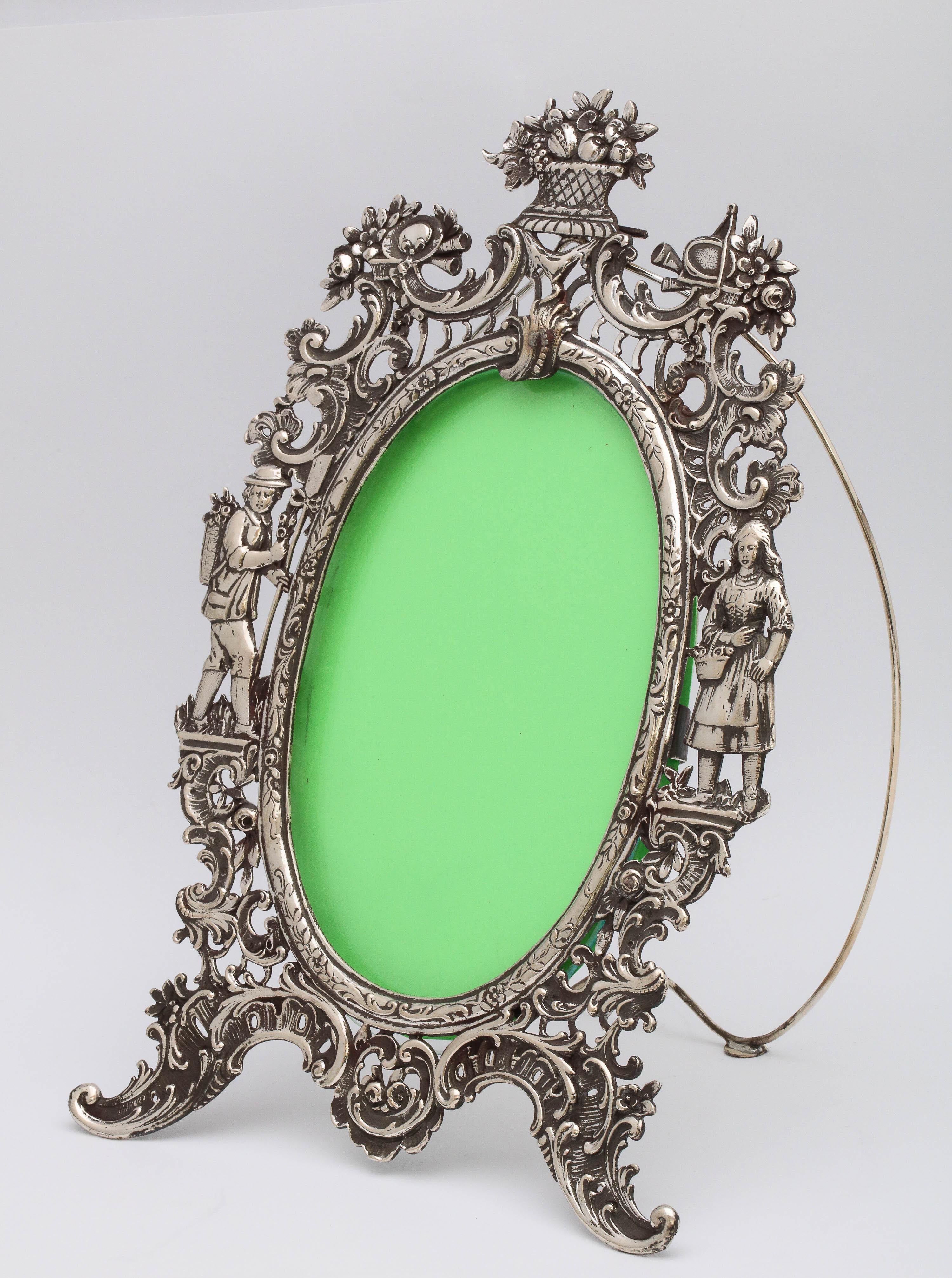 Victorian, Hanau, continental silver (.800) picture frame, Germany, circa 1895, Wolff and Knell - makers. Frame, including the easel, is entirely silver. Decorated with a flower basket (with flowers) at the top; The rest of the frame is decorated