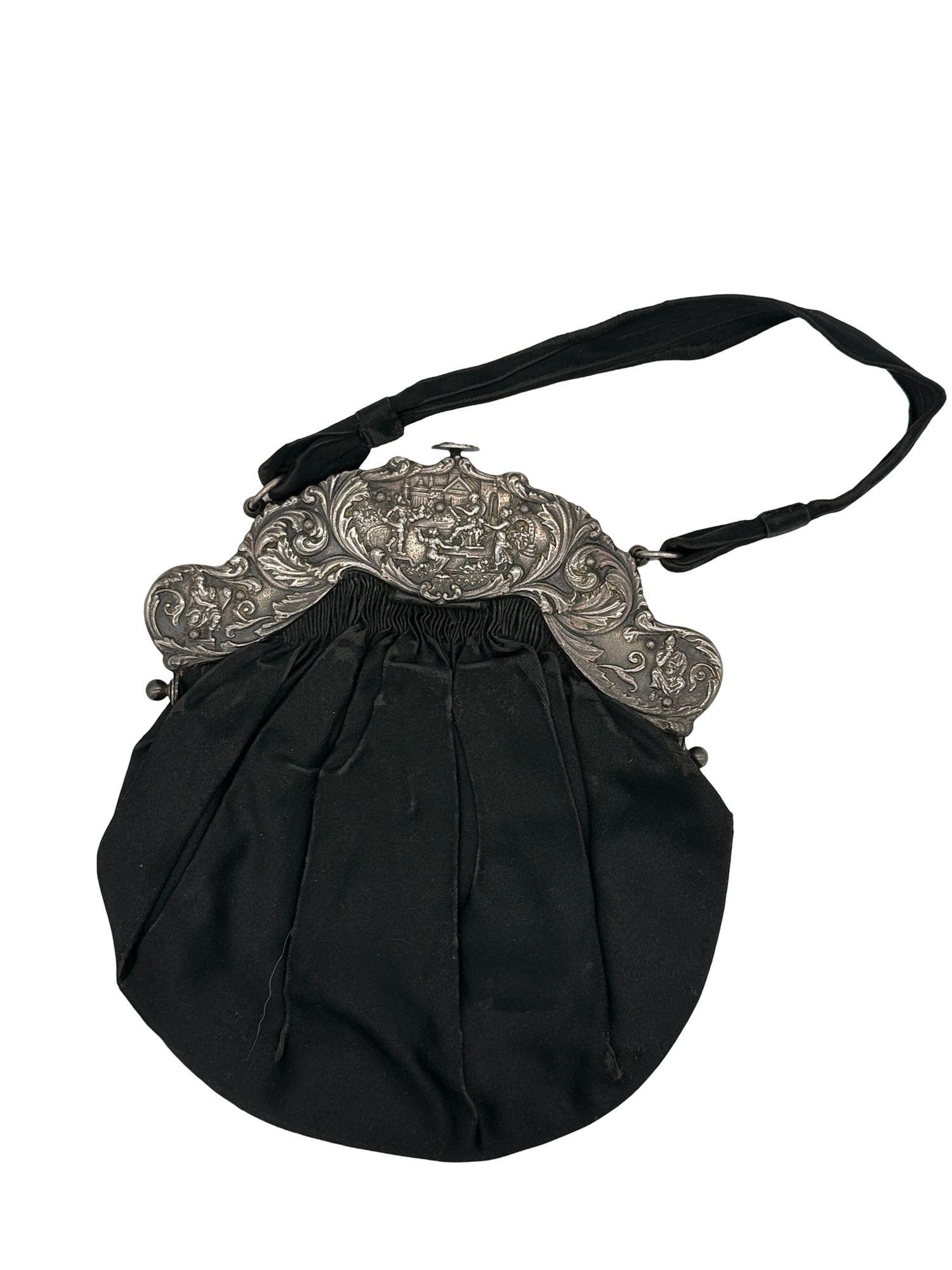 Englische Handtasche mit einem großen dekorativen Verschluss aus Sterlingsilber mit einem religiösen Motiv entlang des Verschlusses.

Punzierungen weisen darauf hin, dass diese Geldbörse 1887 in Birmingham, England, hergestellt wurde. Gestempelt