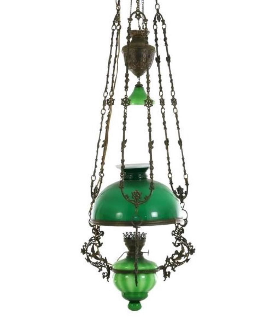 A fine Victorian bronze and green glass hanging oil lamp converted to electric, England, mid-19th century. With a large green hurricane shade and clear glass hurricane chimney. This beautiful lamp comes from a country house library in South West