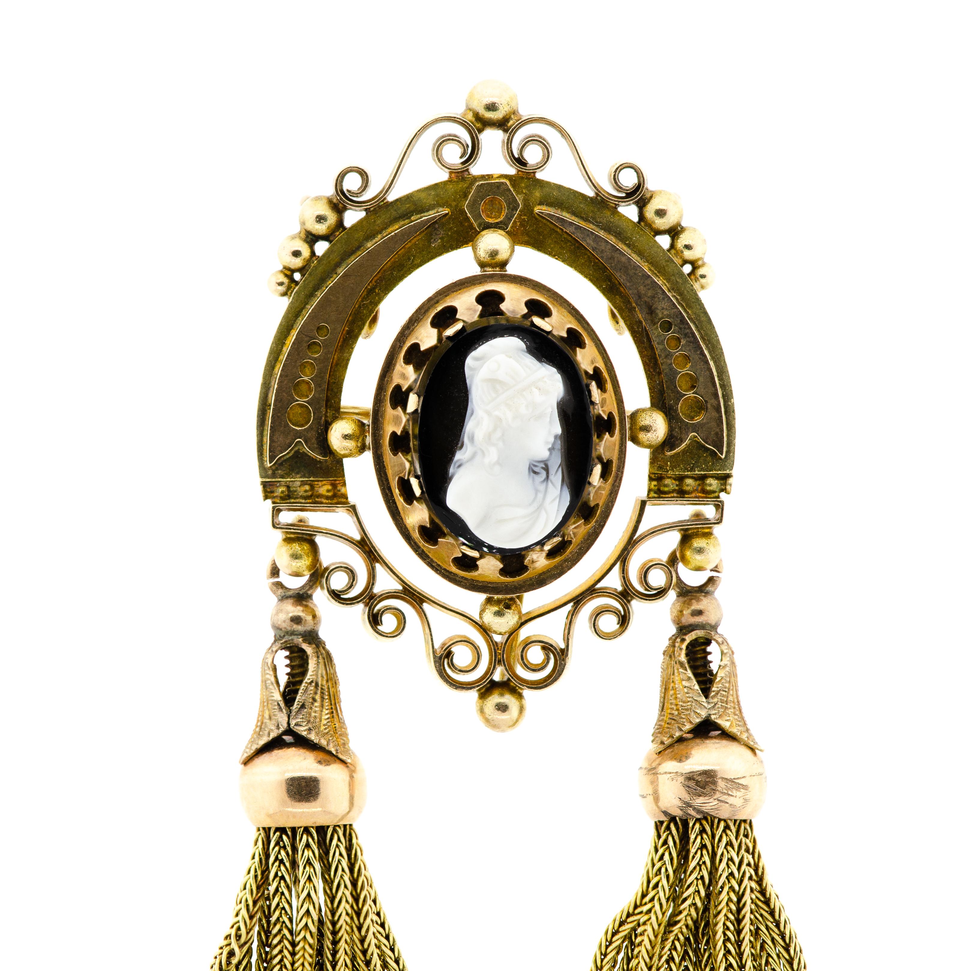 This is a stunning Victorian-era piece of jewelry that dates back to the year 1870. The 14Kt yellow gold and black/white hardstone cameo depicts a beautiful woman in profile and features wonderful tassel drops, as well as lovely scrolled and applied