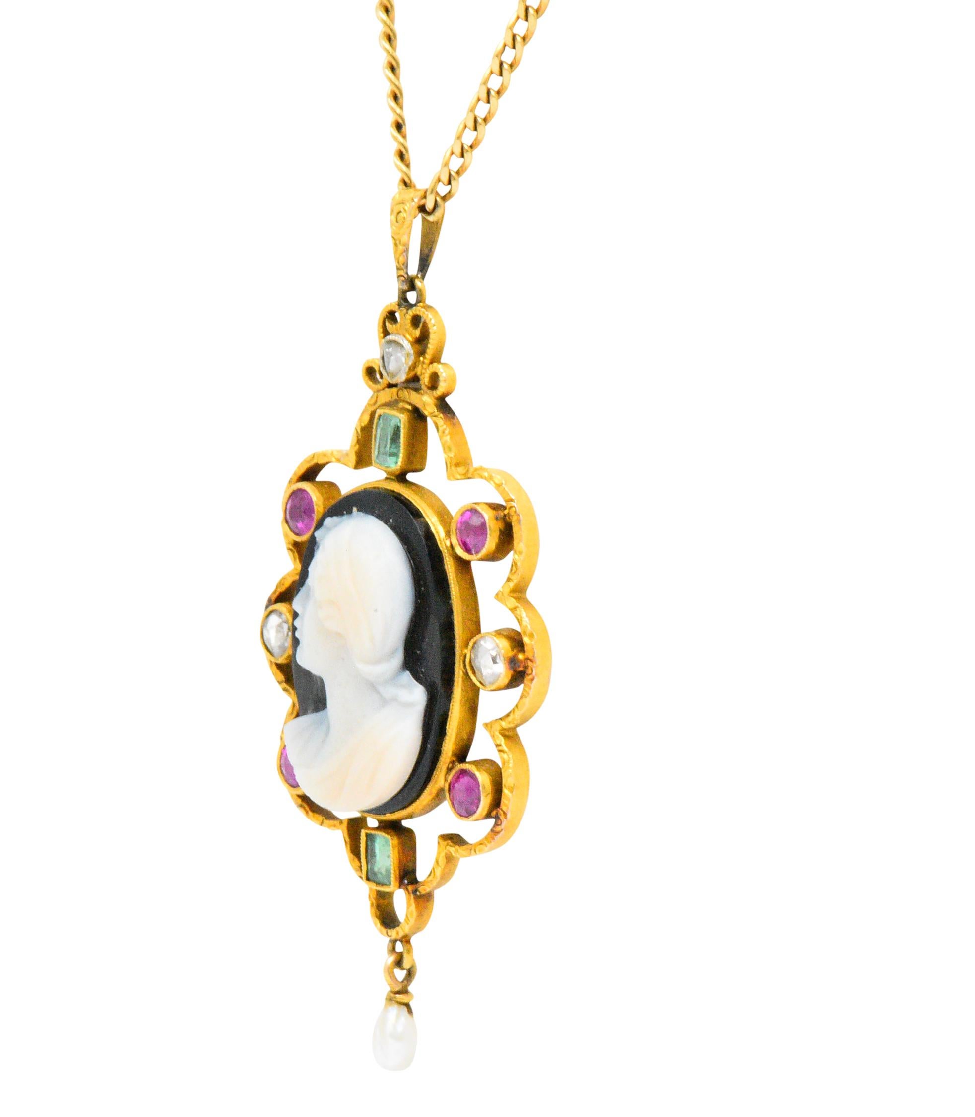 Carved onyx cameo depicting the profile of a woman facing left

Accented with synthetic rubies and natural emeralds

Scalloped engraved gold surround, terminating in a natural baroque pearl

On a 14 karat gold flat open wheat style chain with spring