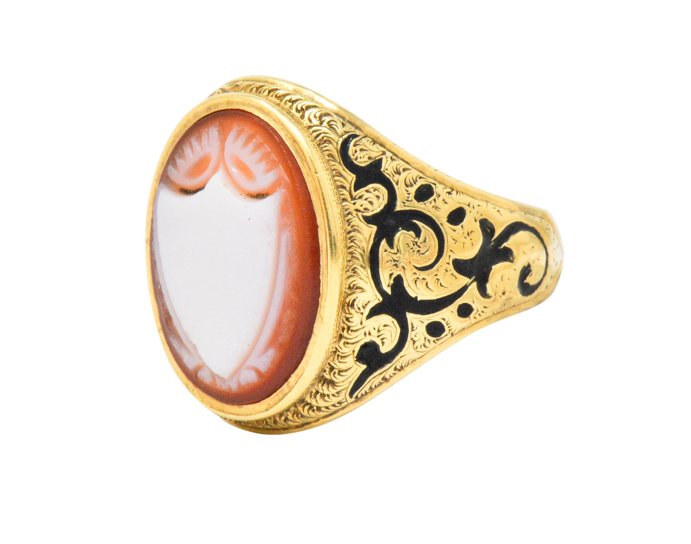 Signet style ring centering an oval cameo of banded carnelian, measuring approximately 14.6 x 11.5 mm

Deeply carved to depict a bright white shield accented by thistle motif, against an orangey-red background

Bezel set low within mounting ornately