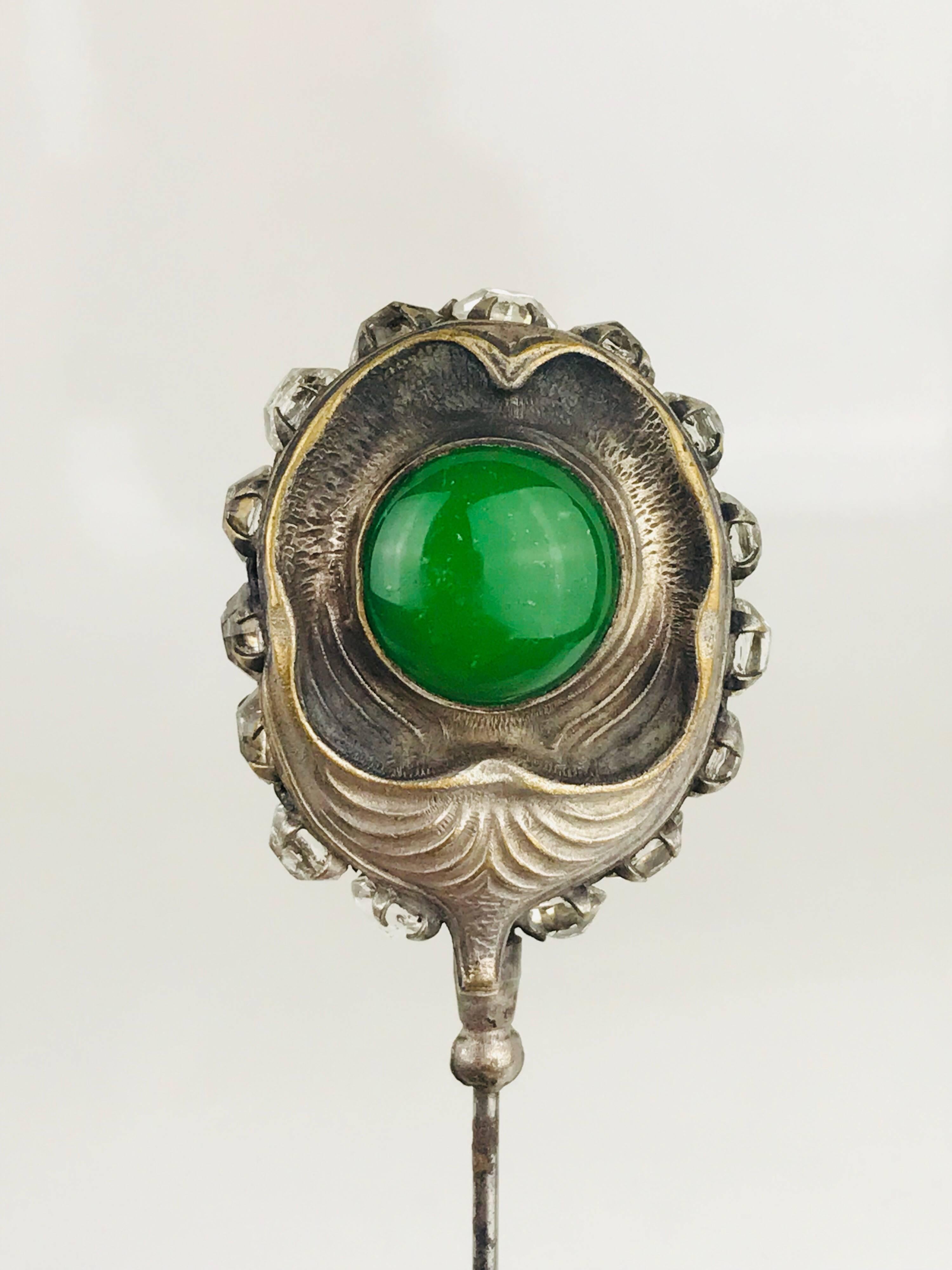 Sterling silver Victorian hat pin, circa 1840, features two large, bezel-set green cabochons  and 15 rose-cut, prong-set rhinestones.  Pinhead is identical on both sides.

Hat pin measures 6.56
