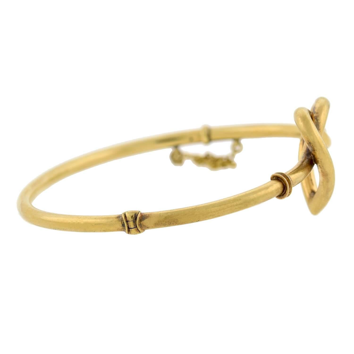 A stunning love knot bracelet from the Victorian (ca1880) era! This gorgeous piece is crafted in 15kt yellow gold and features a heart-shaped love knot design at its center. The knot is formed by a single gold tube which creates the band of the