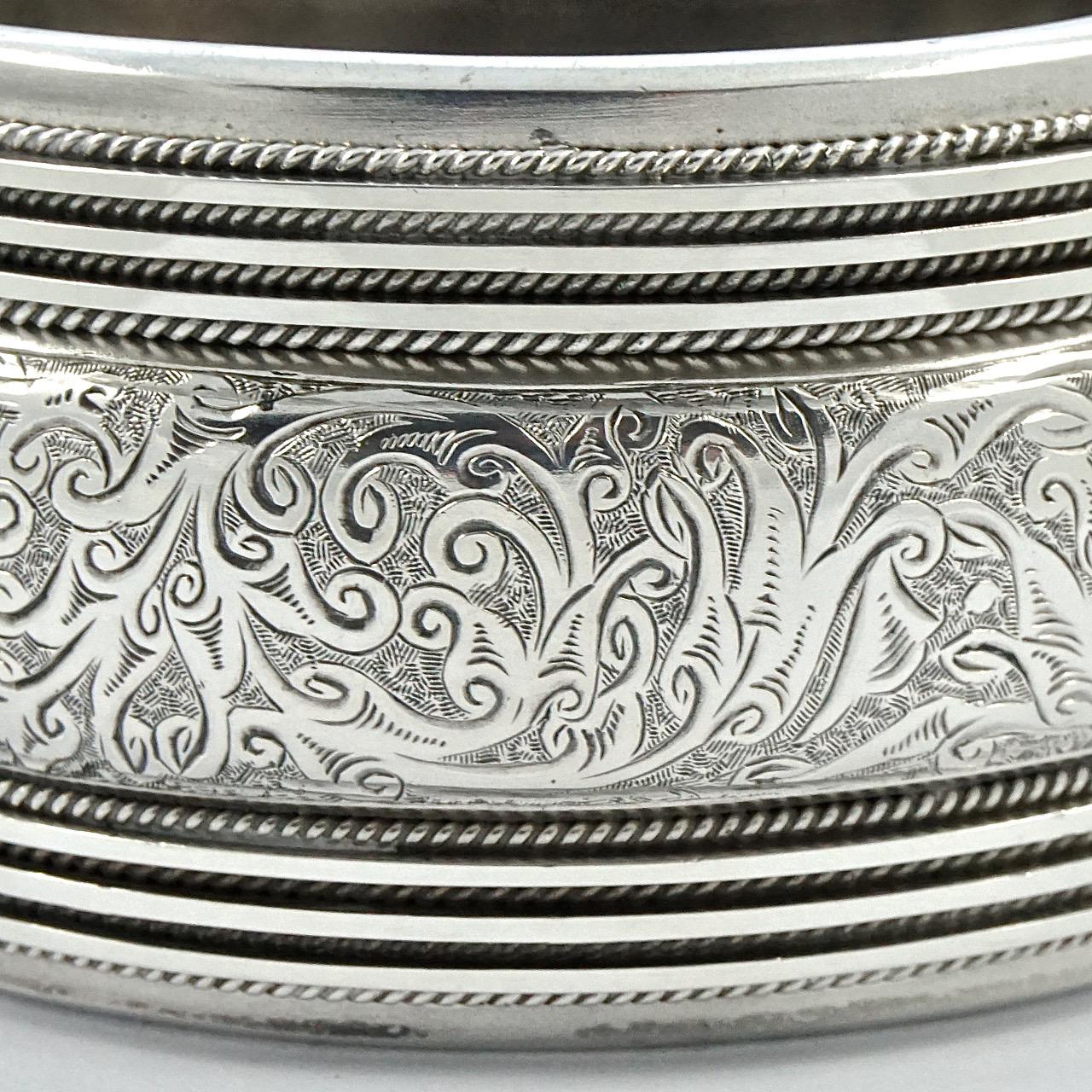 Beautiful Victorian heavy silver bangle, with a lovely engraved raised central panel, and a rope twist and line design to either side. The back has a silky silver sheen. The bracelet tests for silver. It is slightly oval, the inside measurements are