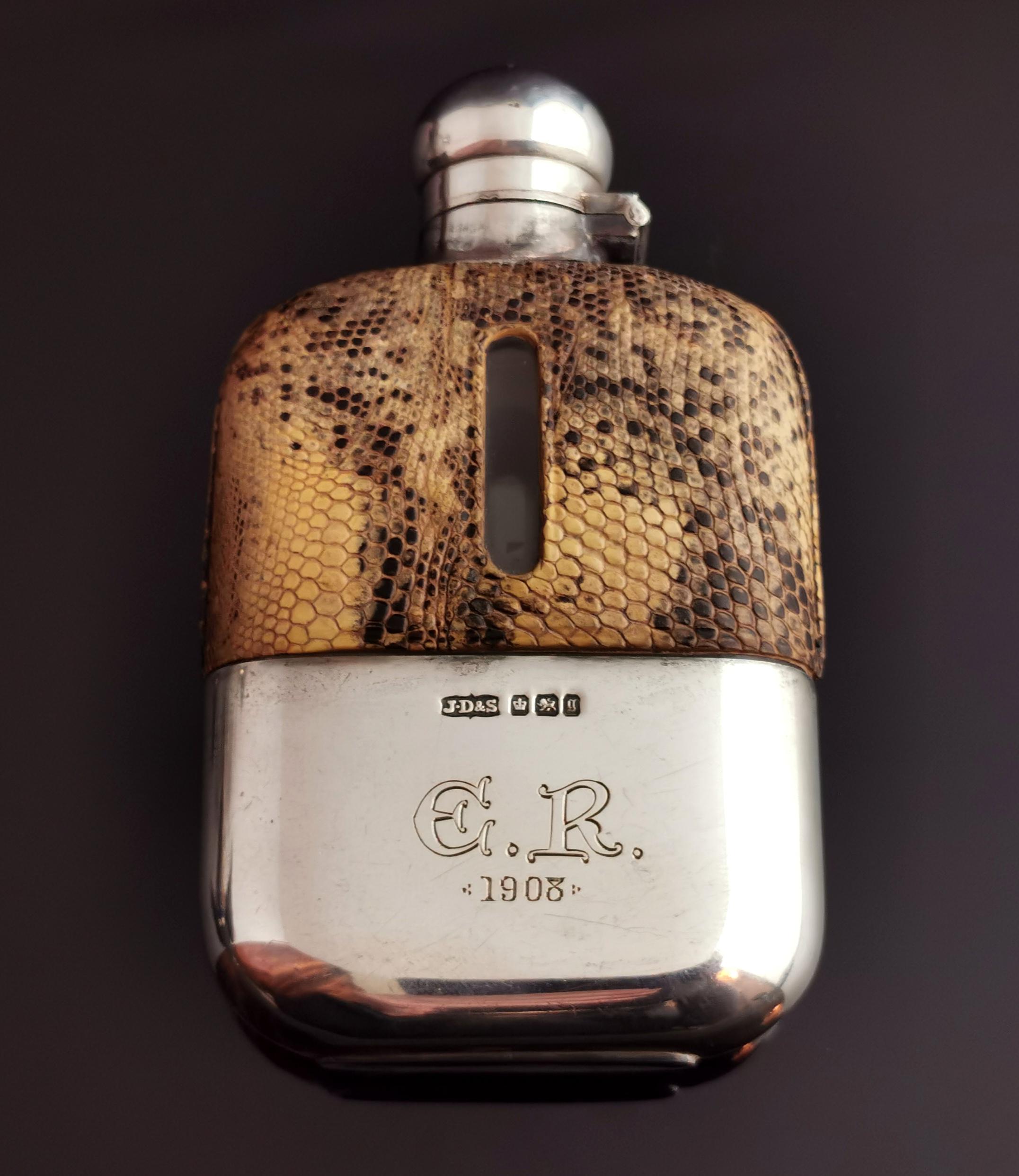 An attractive antique late Victorian sterling silver and faux snakeskin hip flask.

It has a sterling silver lock mechanism cap with the original inner cork, fully hallmarked, the body is made from glass and it has the original gilt lined sterling