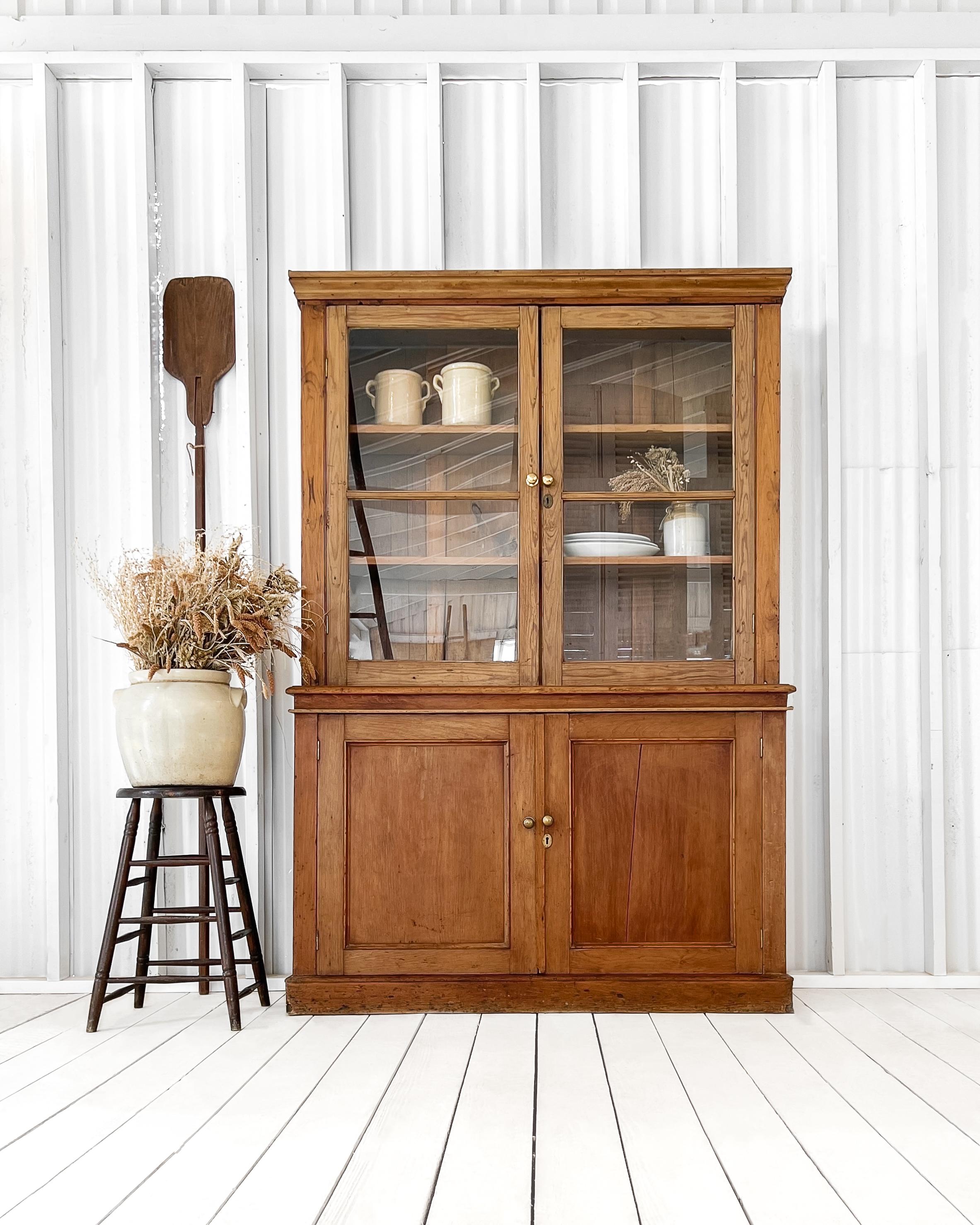 Traditional step-back hutch having handsome, straightforward features. Found in England, circa 1850, and handcrafted from solid English pine. Two adjustable shelves sit behind the glass doors of the upper, while a single shelf is enclosed behind