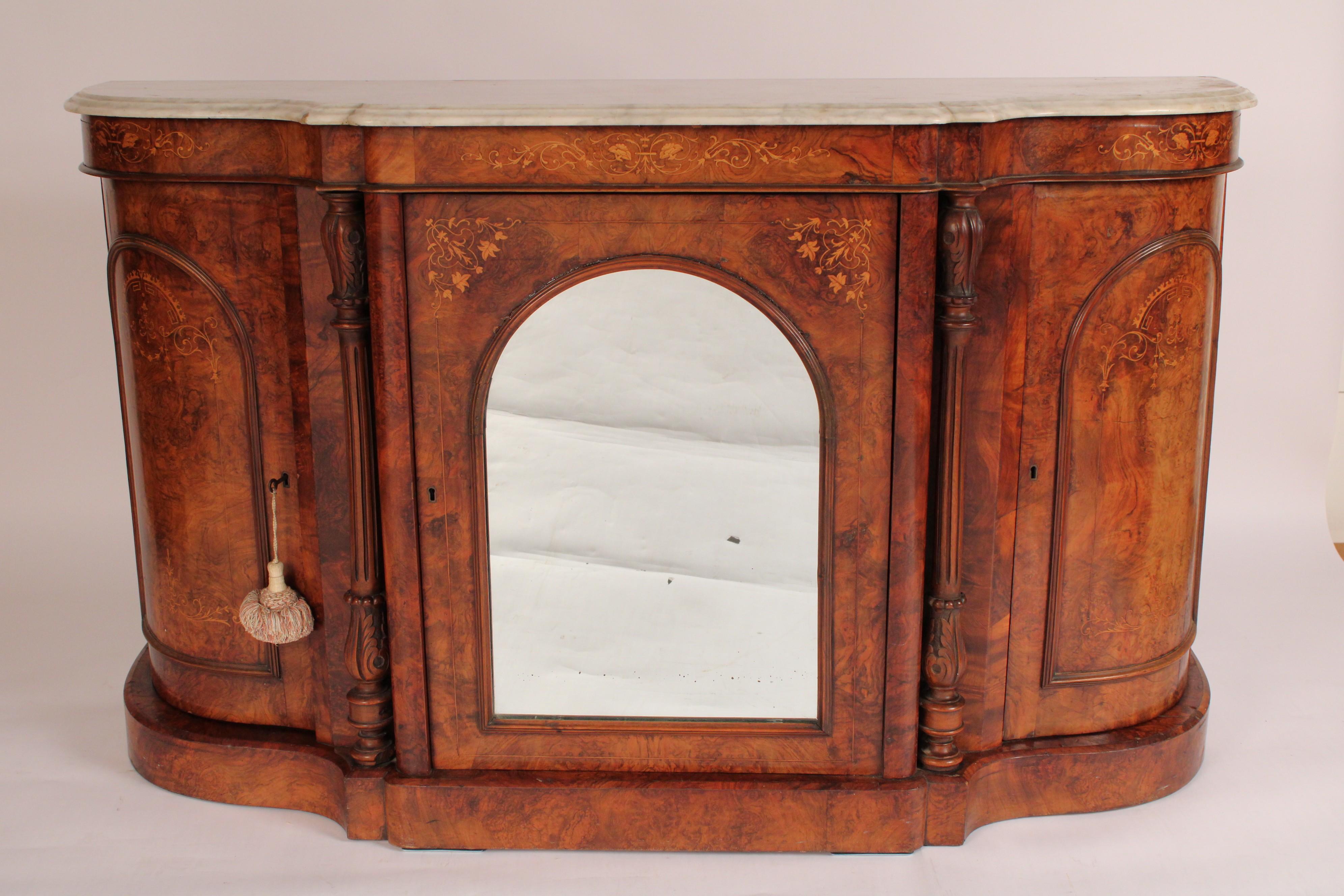 English Victorian inlaid burl walnut sideboard with marble top, circa 1880. With a carrera marble top with molded edges, a frieze with vine inlay, a central mirrored door with inlay, flanked by floral carved and fluted columns, inlaid burl walnut
