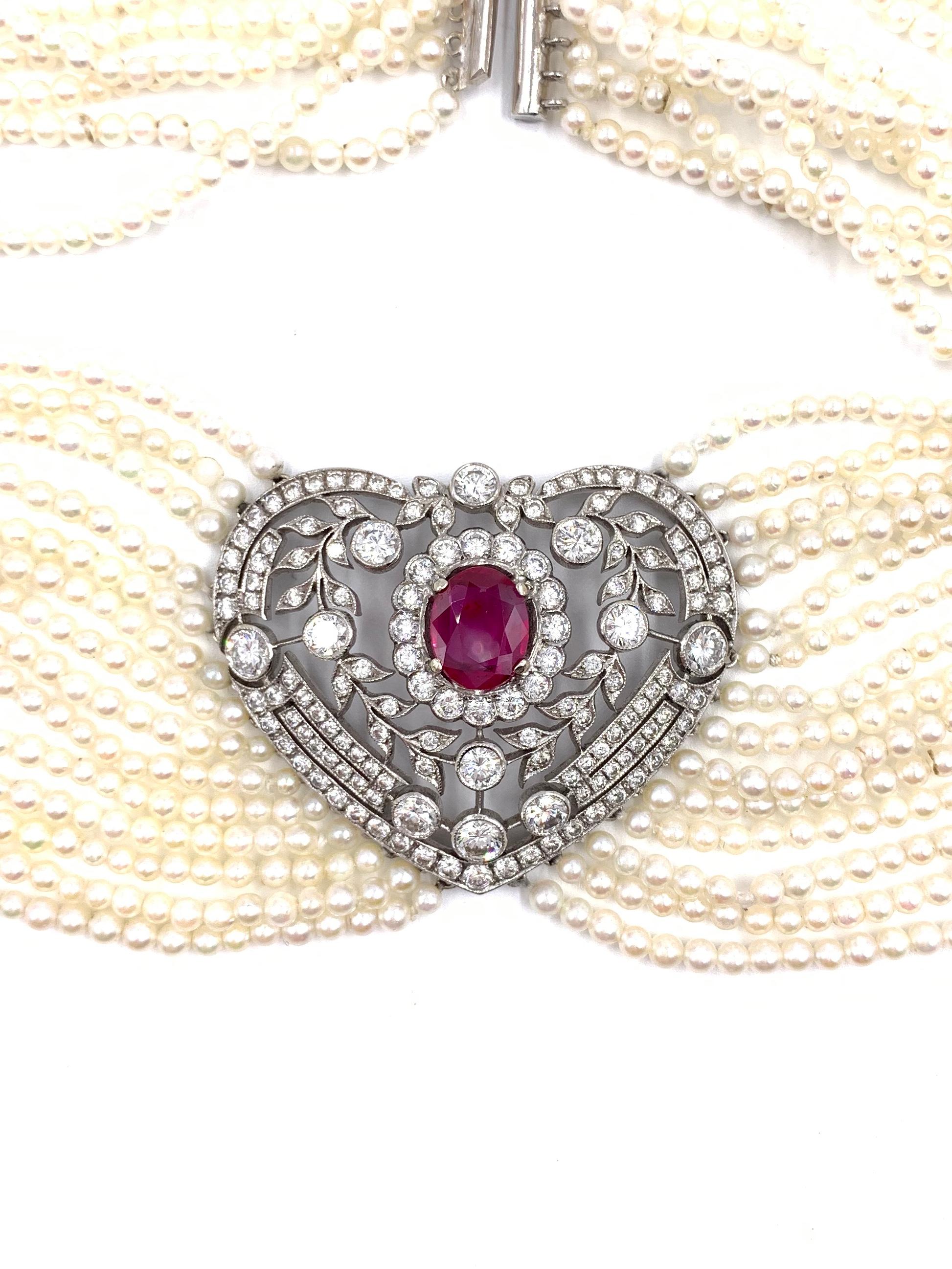 An exquisite and highly saturated approximate 2 carat oval red ruby is the centerpiece of this 14k white gold filigree and diamond heart shape pendant stationed at the center of an elegant 14-strand Victorian-inspired choker style necklace. The