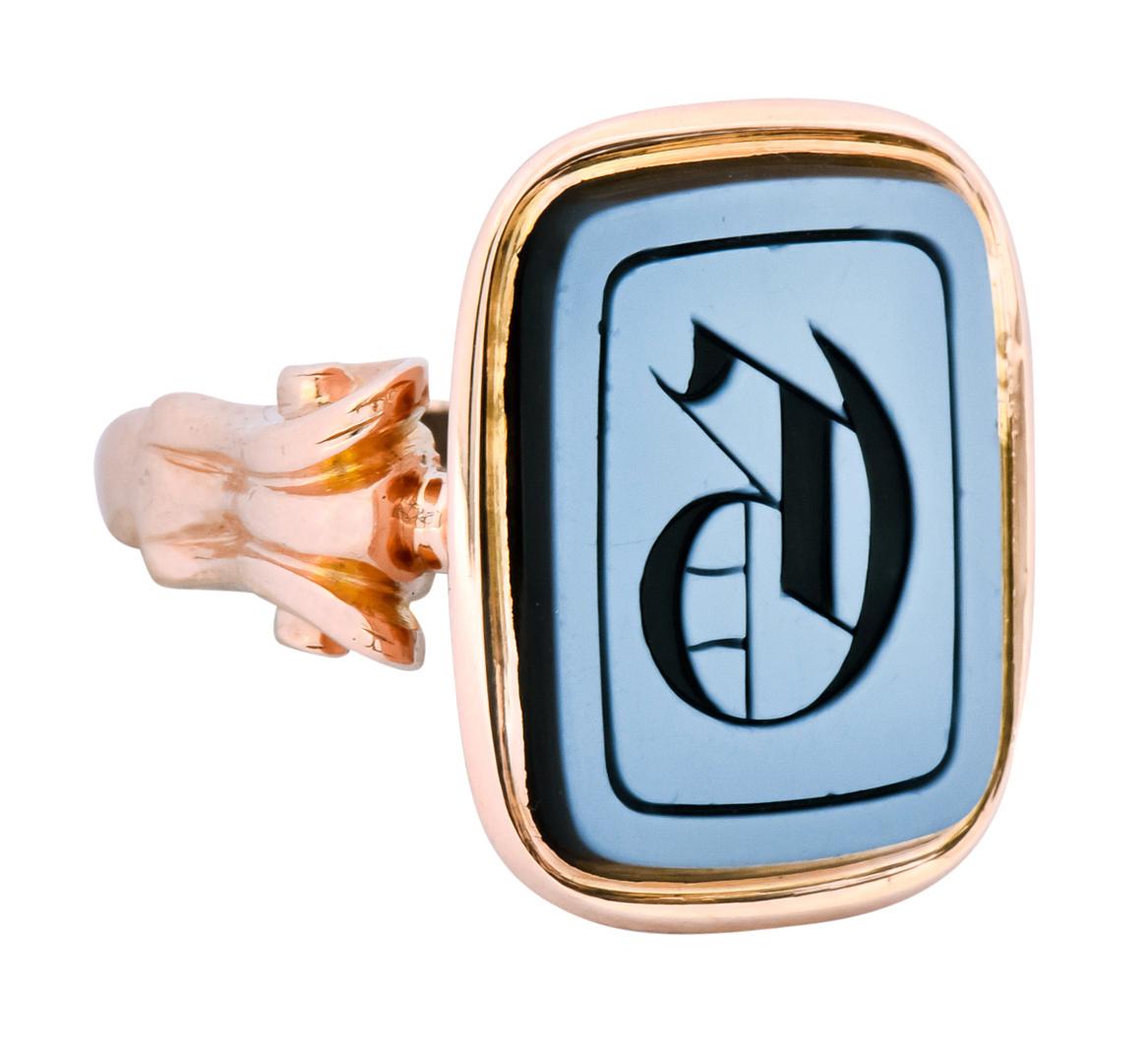 Centering a reverse carved intaglio displaying an uppercase 'G', measuring approximately 16.5 x 12.5 mm

With a white surface, black back, and the deeply engraved stylized black 'G'

Bezel set in a polished gold surround with milgrain detailing,
