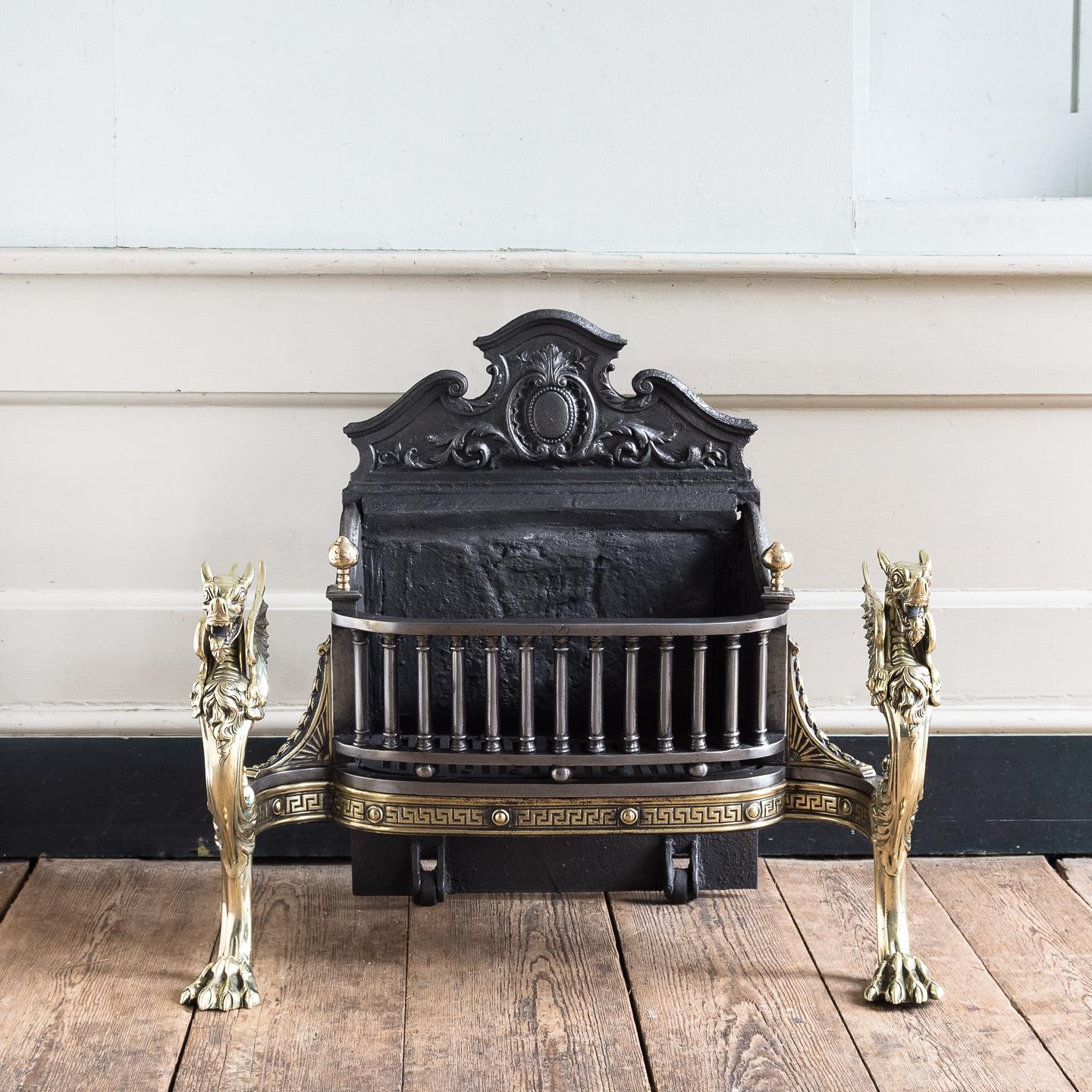 A Victorian iron and brass Griffin fire grate, the Rococo backplate centered by cabochon, the grate composed of a run of Doric columns with a Greek key apron band below, all supported on finely cast brass Griffin monopodia with hairy paw feet.