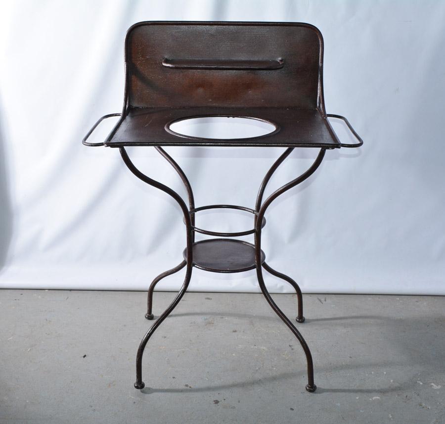 The Victorian dark brown iron metal washstand can be used as is or as a plant stand with the appropriate pot placed in the hole. The back splash holds a small shelf. The iron has been given a rust-proof finish. Towel racks protrude from each side.