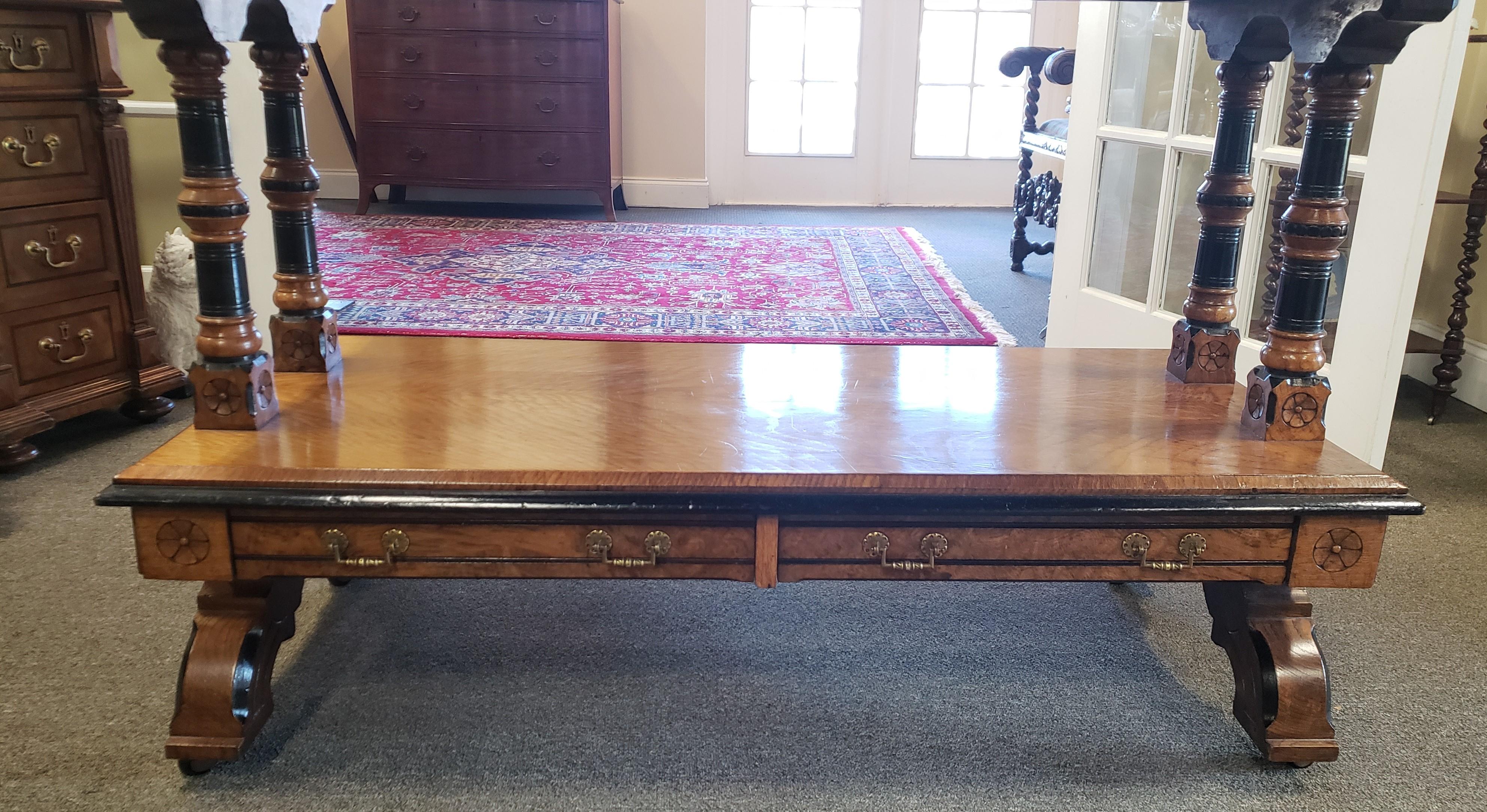 Victorian Jacobean Revival oak and ebonized dumbwaiter. This piece consists of 3 tiers raised and divided by turned and part-ebonized supports on flower head carved blocks. The base has 2 drawers, raised on arched trestle bases with ceramic castors.