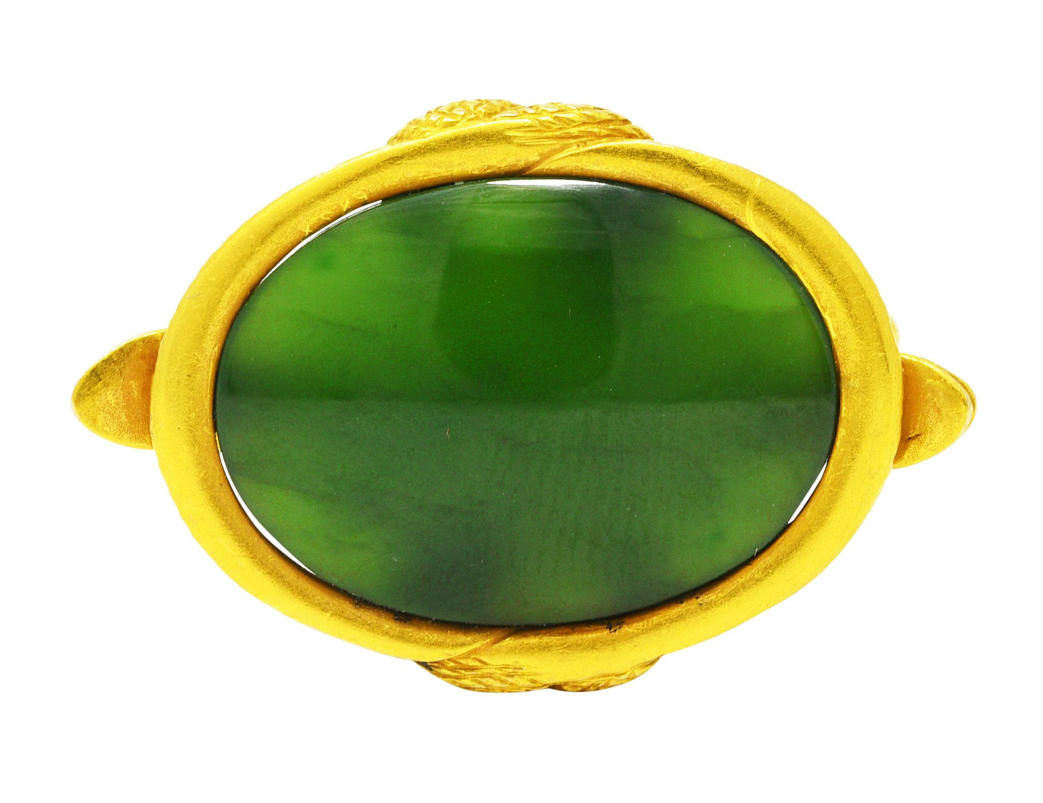 Fob pendant is designed as four swirling gold snakes with engraved scale pattern. Featuring a bezel set jade double cabochon measuring 15.0 x 20.0 mm. Translucent medium green with dark green swirling. Completed by jump ring bale. Tested as 18 karat