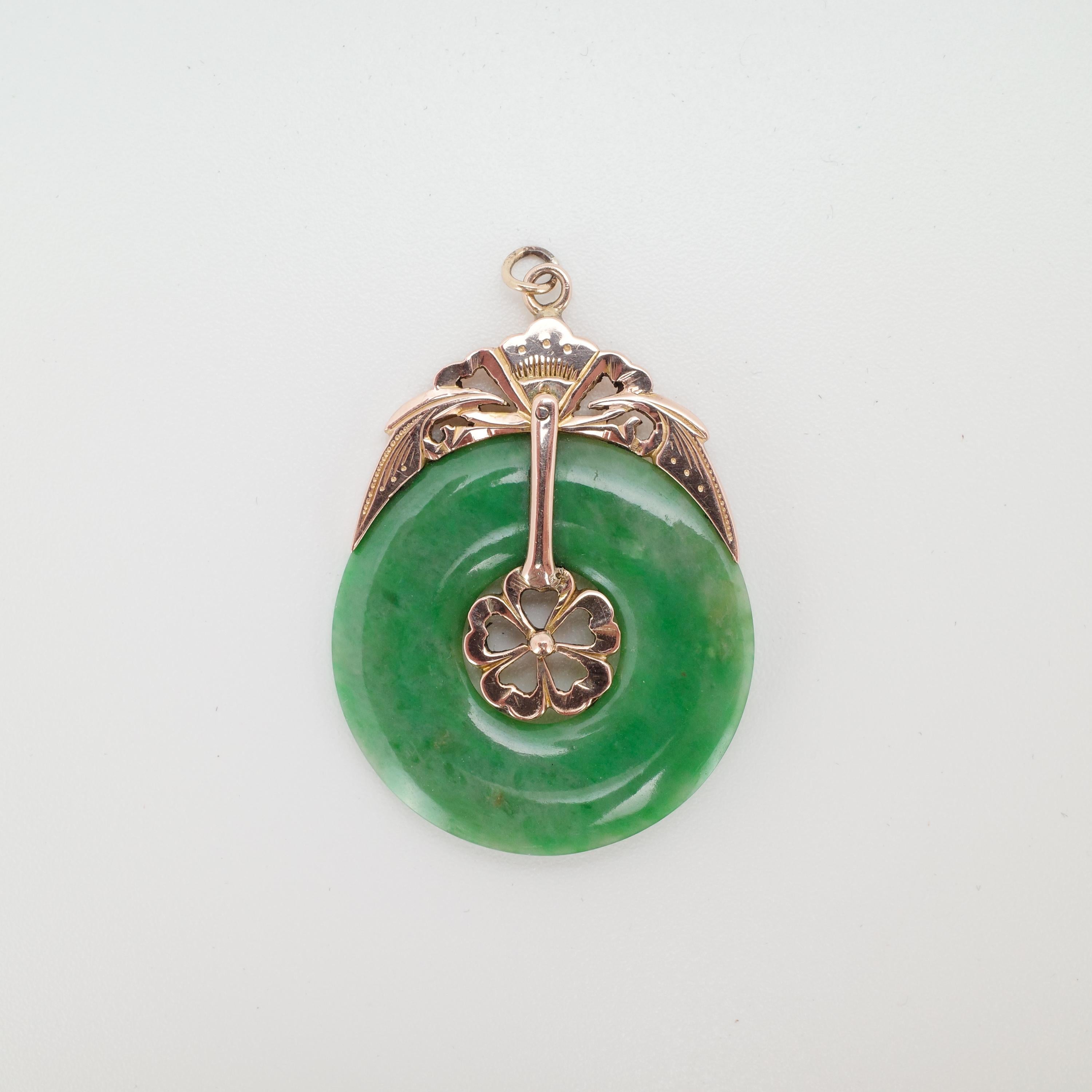 A certified natural and untreated Burmese jadeite jade hololith (a ring made from one piece of stone) is adorned with a handmade 18K rose gold bail that attaches to the jade through the clever design of five hearts in the central hole. The rest of