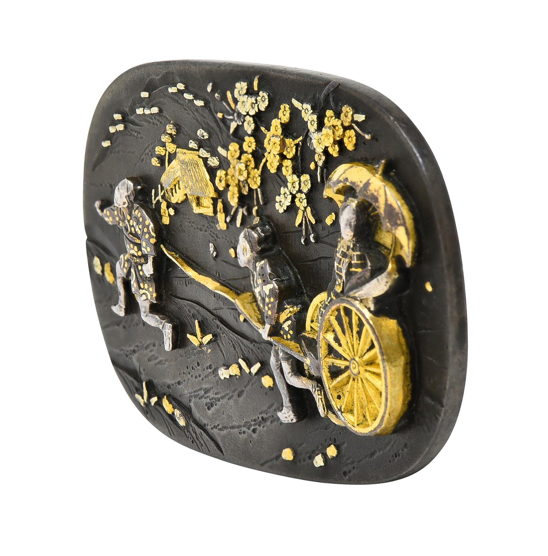 Designed as an oval-shaped form decorated with a raised cameo of Japanese scenery
Depicting cherry blossom trees, a house, and two men pulling a woman in a cart with an umbrella
Engraved and grooved with texture throughout - Shakudo style
Comprised