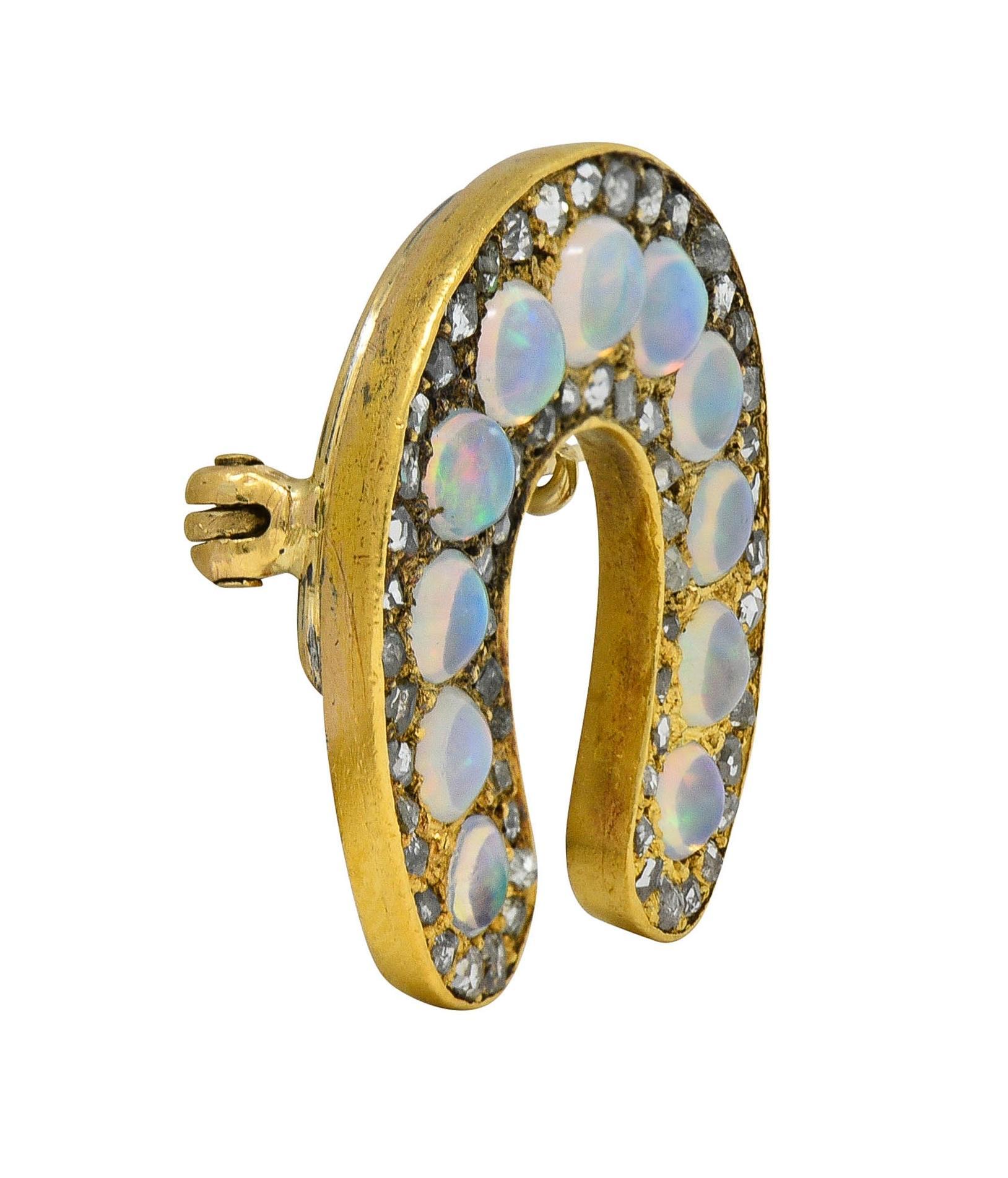 Designed as a horseshoe form featuring a row of jelly opal cabochons
Transparent colorless body with spectral play-of-color
Ranging in size from 2.5 to 3.5 mm round 
Bead set with halo of rose cut diamonds 
Weighing approximately 0.36 carat