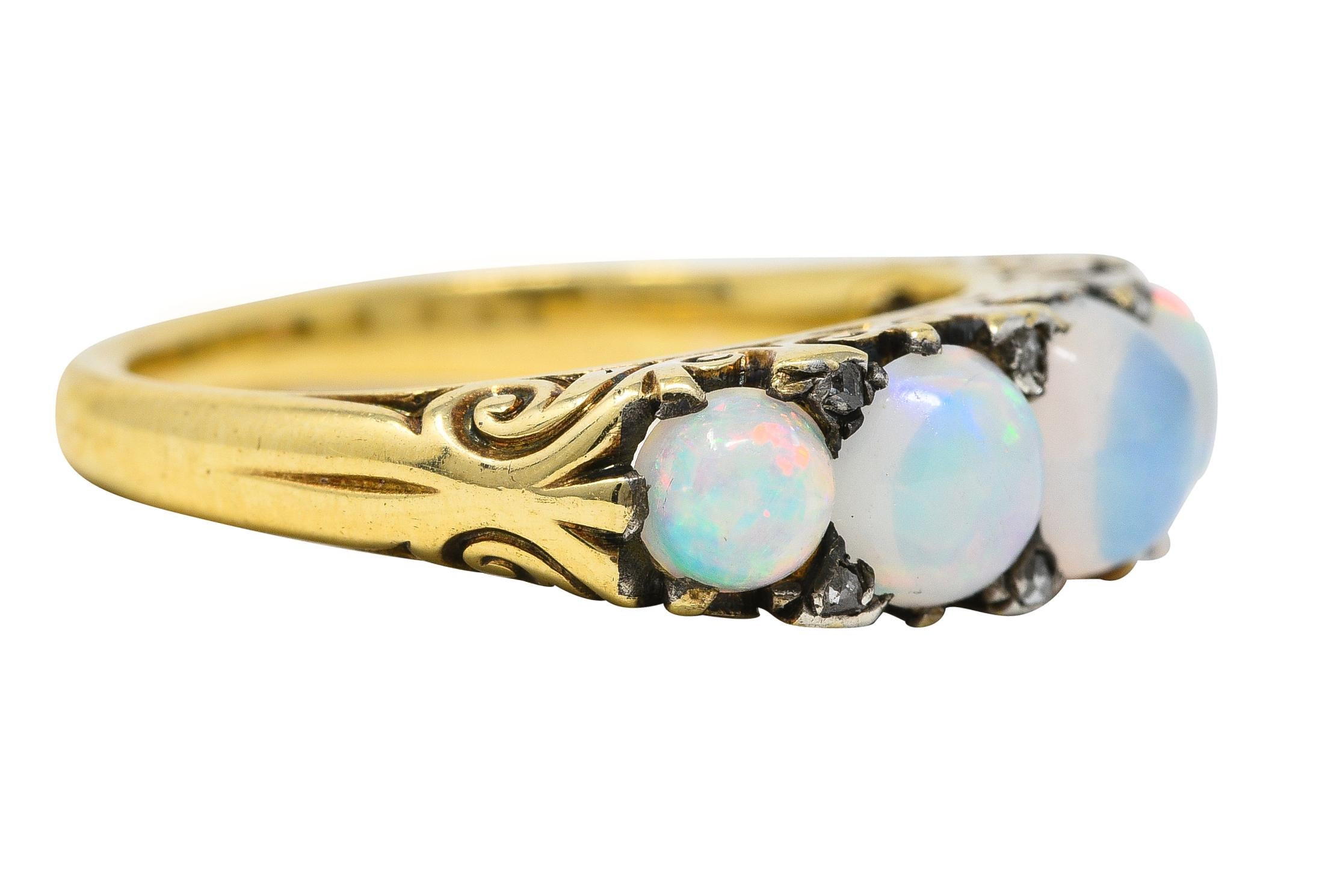 Five stone ring centers a prong set 5.0 mm cushion shaped opal cabochon. Flanked by prong set round graduated opals on either side - ranging from 4.8 to 3.5 mm. Well matched white in body color with very strong spectral play-of-color. Accented by