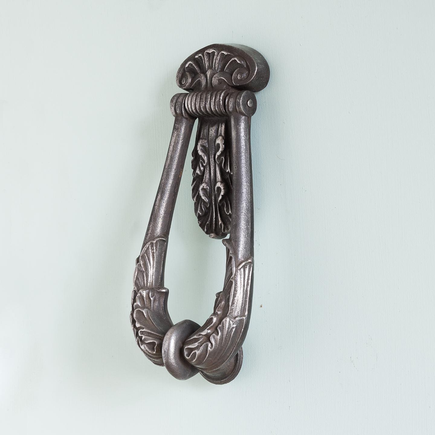 A Victorian cast iron door knocker made by Kenrick, of looped form with acanthus backplate, stamped 'A. Kenrick & Sons 365'.