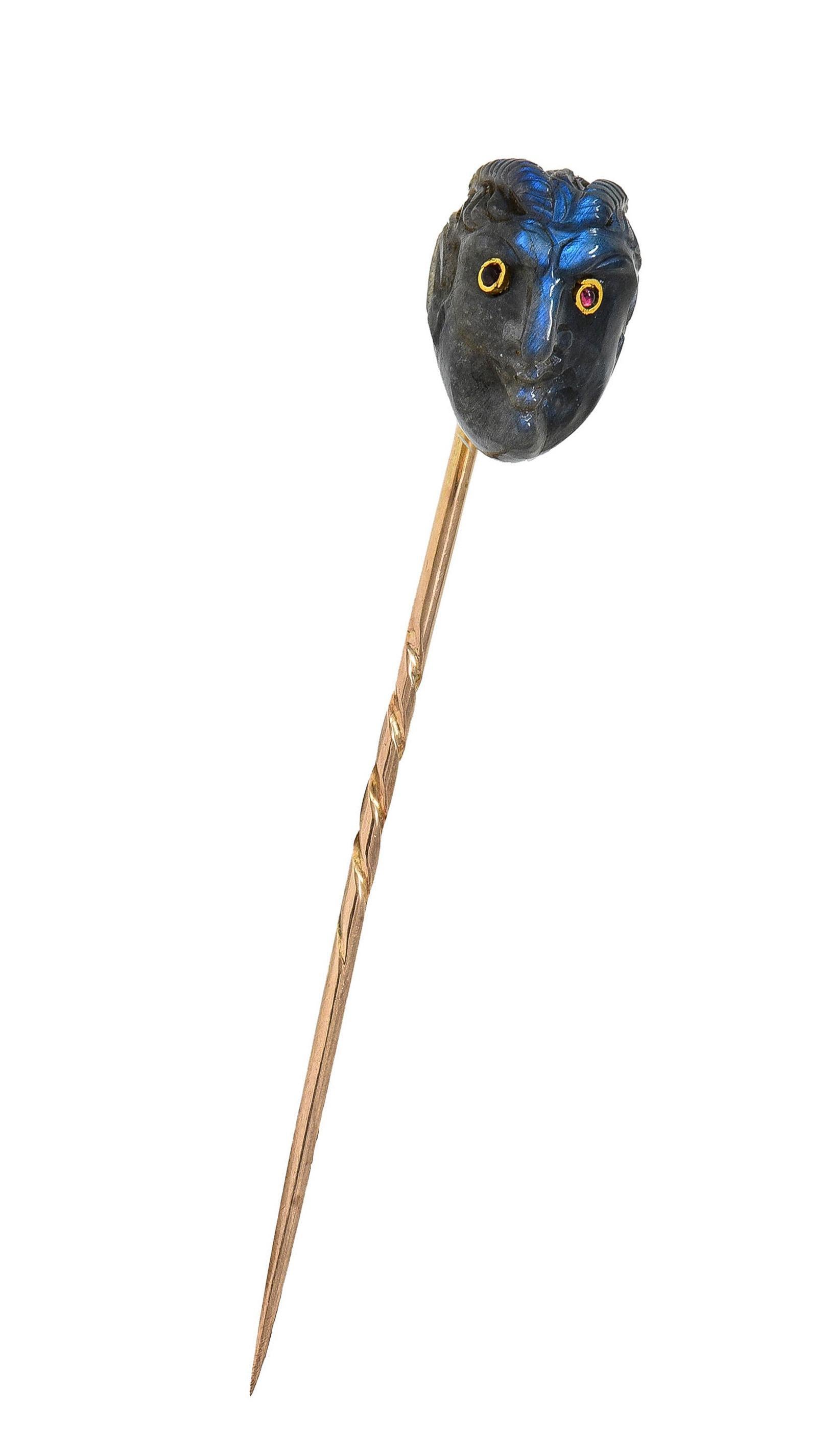 Designed as a stylized devil with textured horns- carved out of labradorite
Semi-translucent gray in body color with strong adularescence - blue flashes throughout
With bezel set ruby eyes - translucent red in color
Completed with pin stem
Tested as