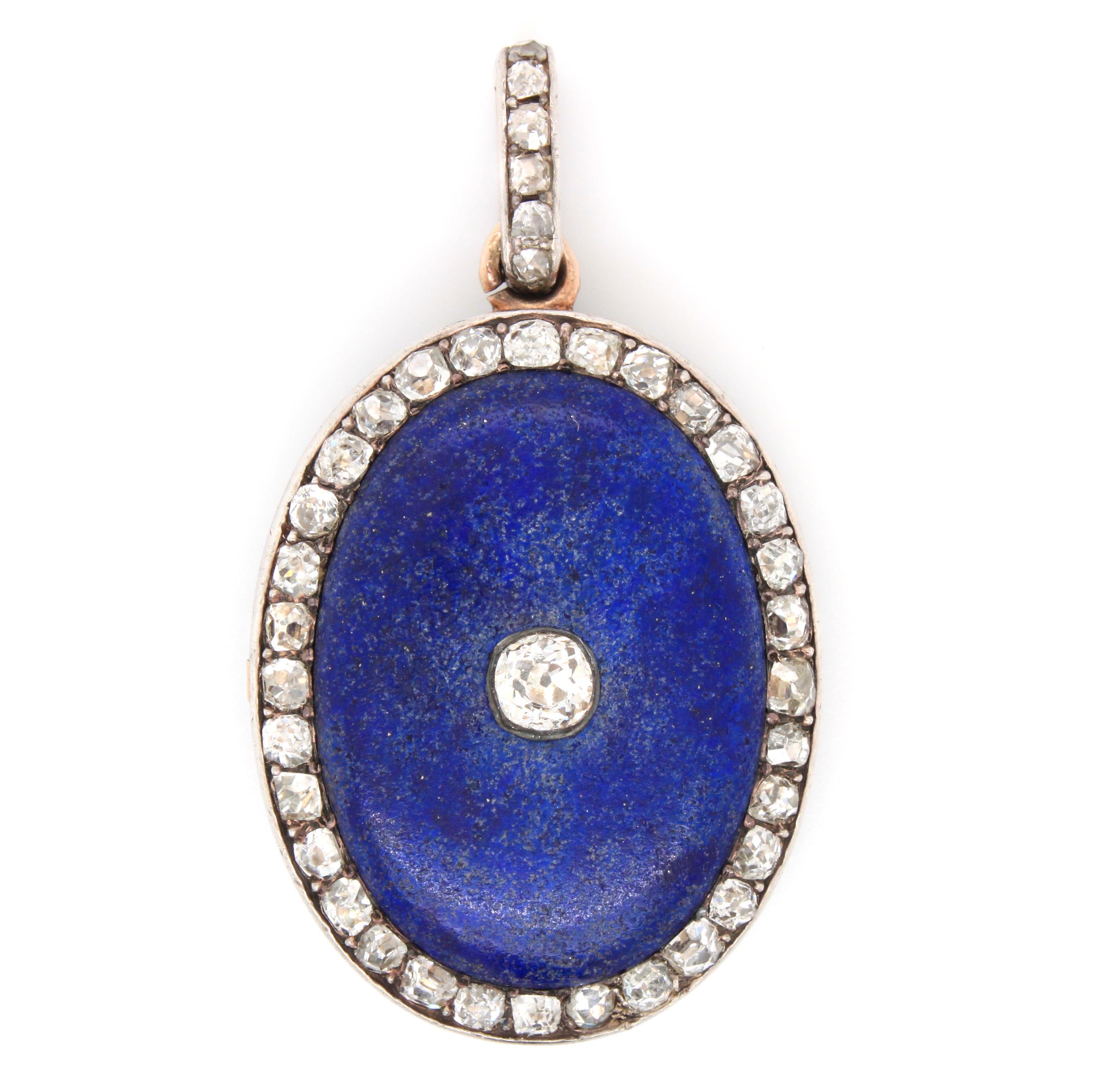 An antique Victorian oval-shaped lapis lazuli and old cut diamonds locket pendant, circa 1880s. The locket looks the same on the front and reverse side. It opens up to display a photo frame under a glass covering. The pendant has French gold and