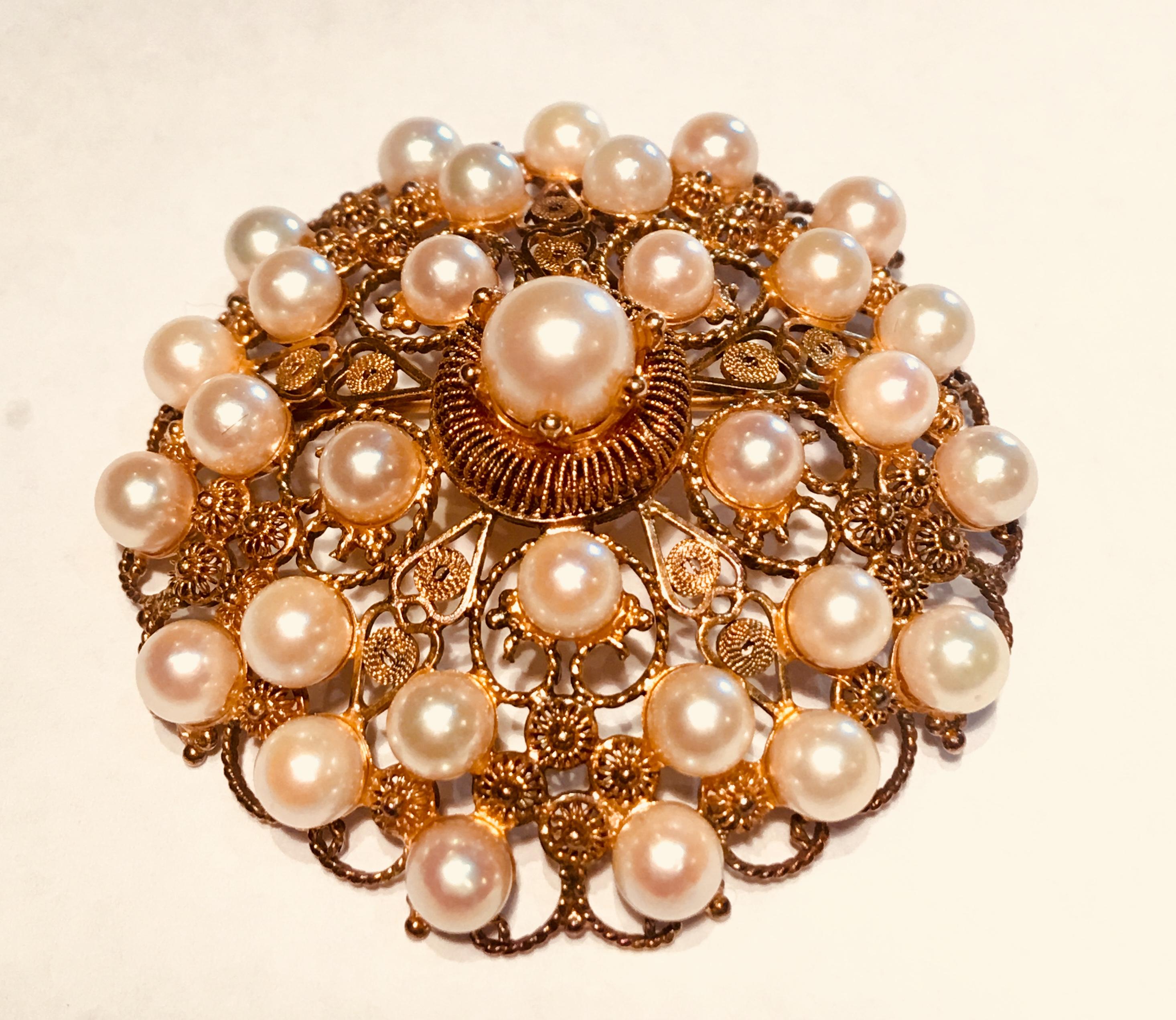 Lovely antique, late Victorian, handmade 14 karat gold filigree brooch pin pendant from the late 1800s is large, round and convex shaped, featuring 31 round, lustrous golden hued saltwater pearls and a generous sized, hinged bale to wear it on a
