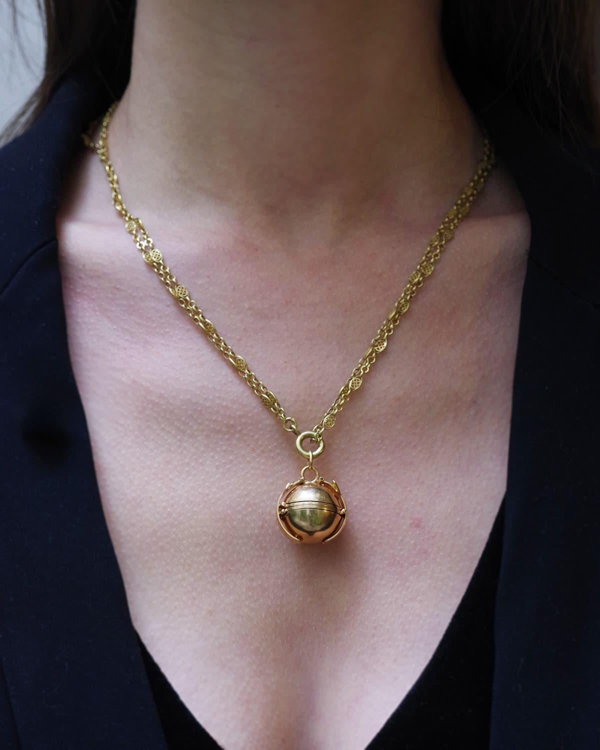 Victorian locket ball pendant in 18 karat gold. A rare folding pendant that takes the form of a sphere, decorated on either side with bands that hold it closed. This is a photo locket pendant: the two bands unclip to reveal a series of four frames.