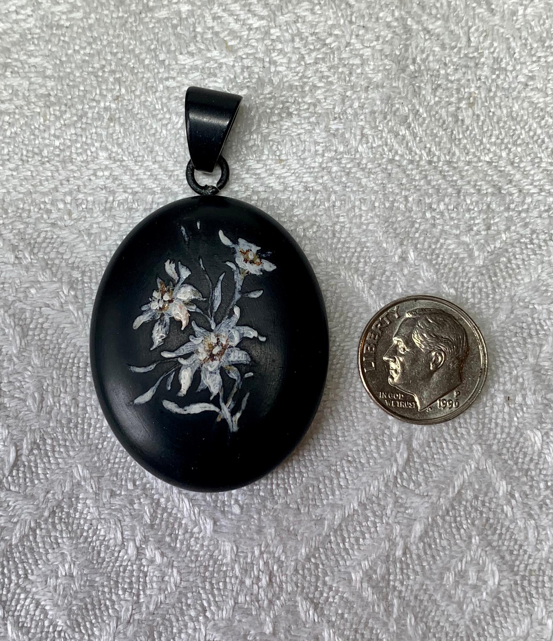 A rare and wonderful Victorian Locket pendant with gorgeous hand painted enamel of an Edelweiss Flower motif.   The locket is Black Whitby Jet.  It has a Jet bale.  The reverse has a lovely photo compartment.  The gilded insert can be removed and a