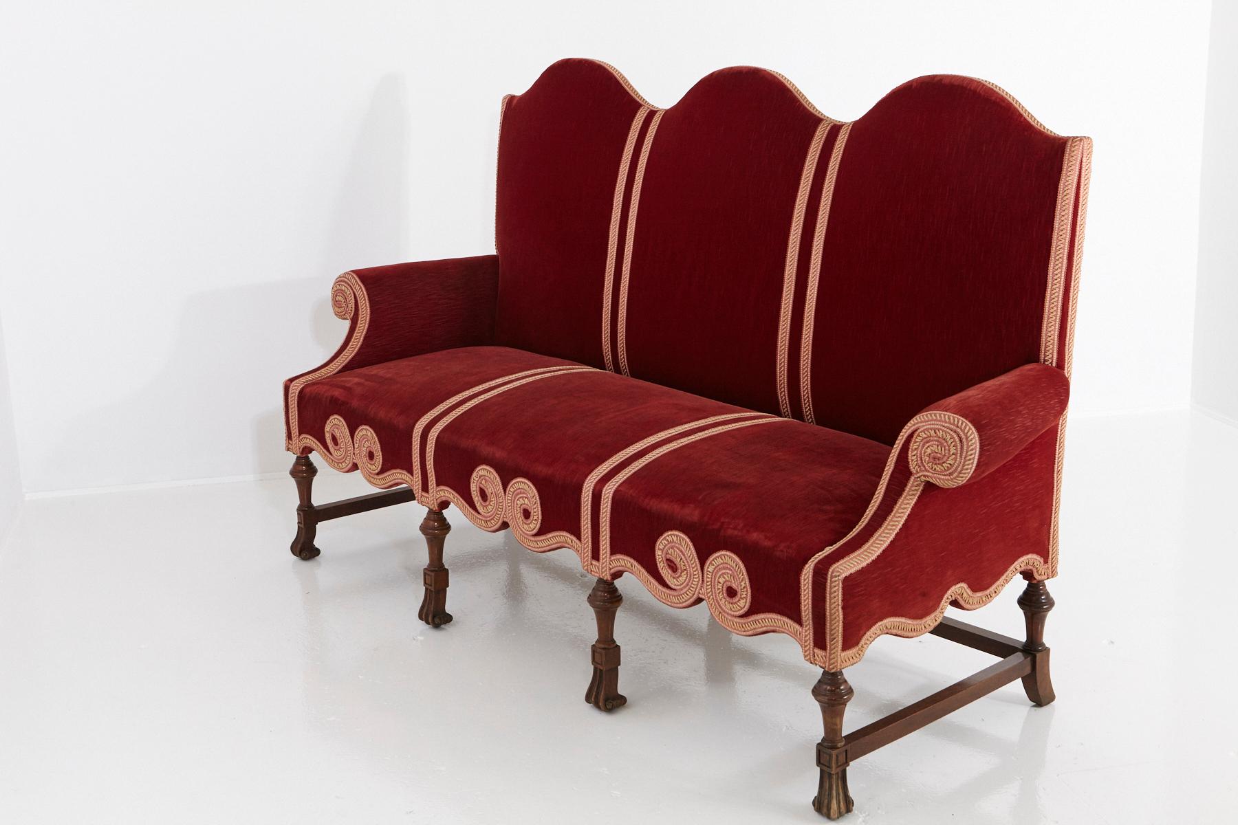 Late 19th century Victorian long seat sofa with scrolled arms and camelback upholstered in red striae velvet, with gild embroidered piping ribbons, creating a graphic pattern and scrolled elements, mounted on carved legs with scrolled feet and side
