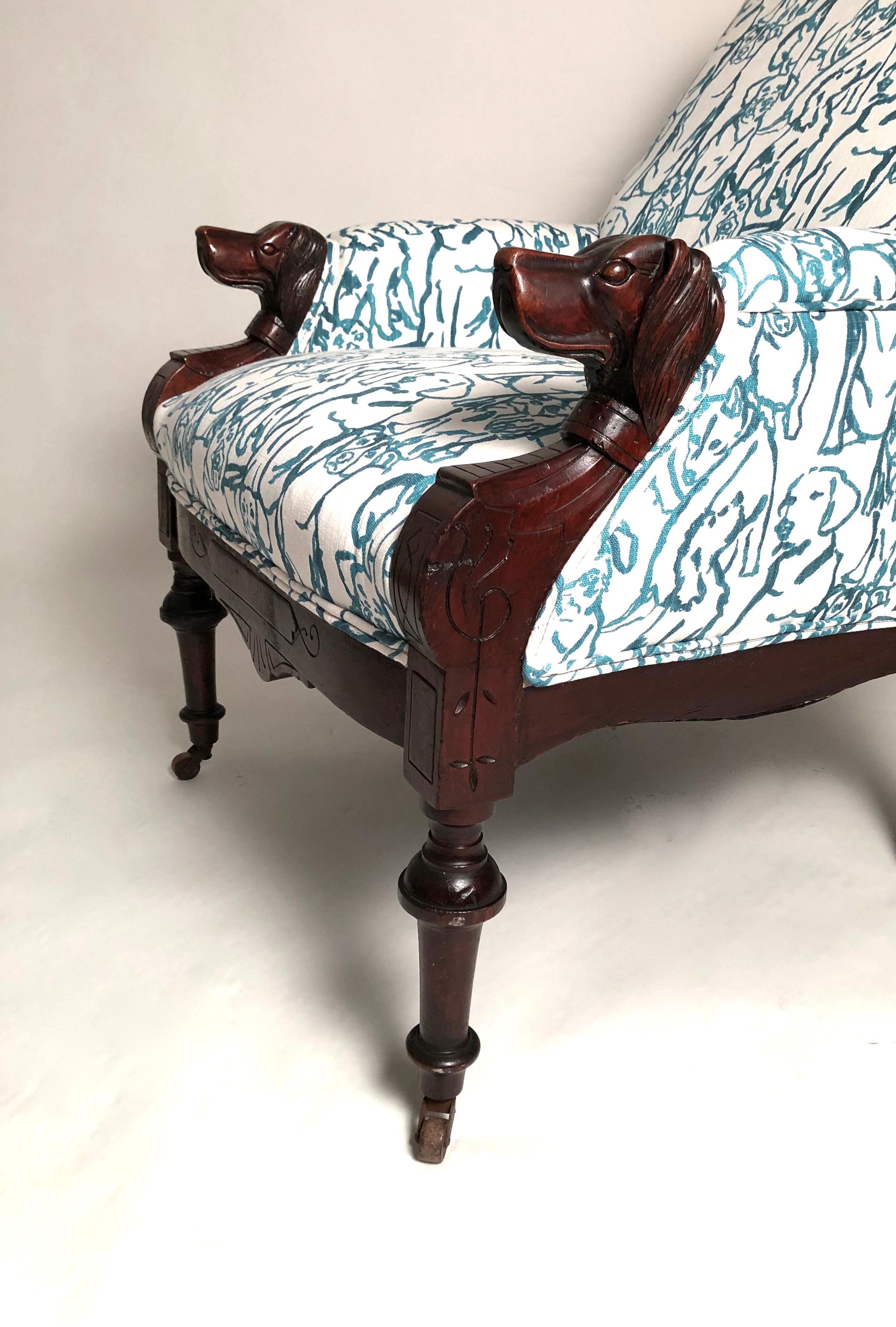 A very comfortable and well proportioned Victorian armchair, circa 1875-1880, with carved dog head armrests in mahogany, newly upholstered in a blue and white printed cotton fabric with charming dog illustrations on it. The ends of the armrests are