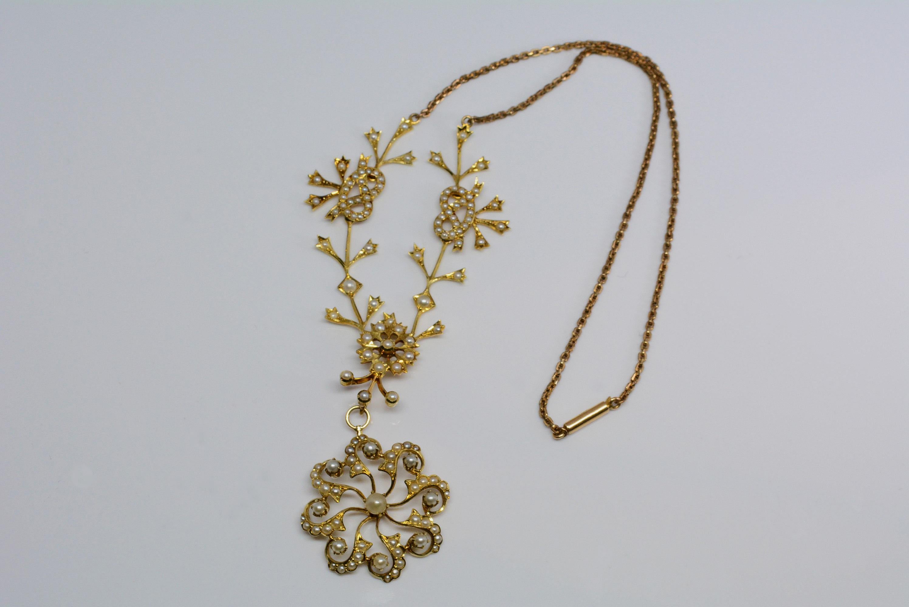 This necklace is made from 14 karat yellow gold and has seed pearls set throughout the piece with love knot and bow motifs. 
These motifs symbolized endless love in the victorian era, along with the large centrepiece that has a floral motif which is