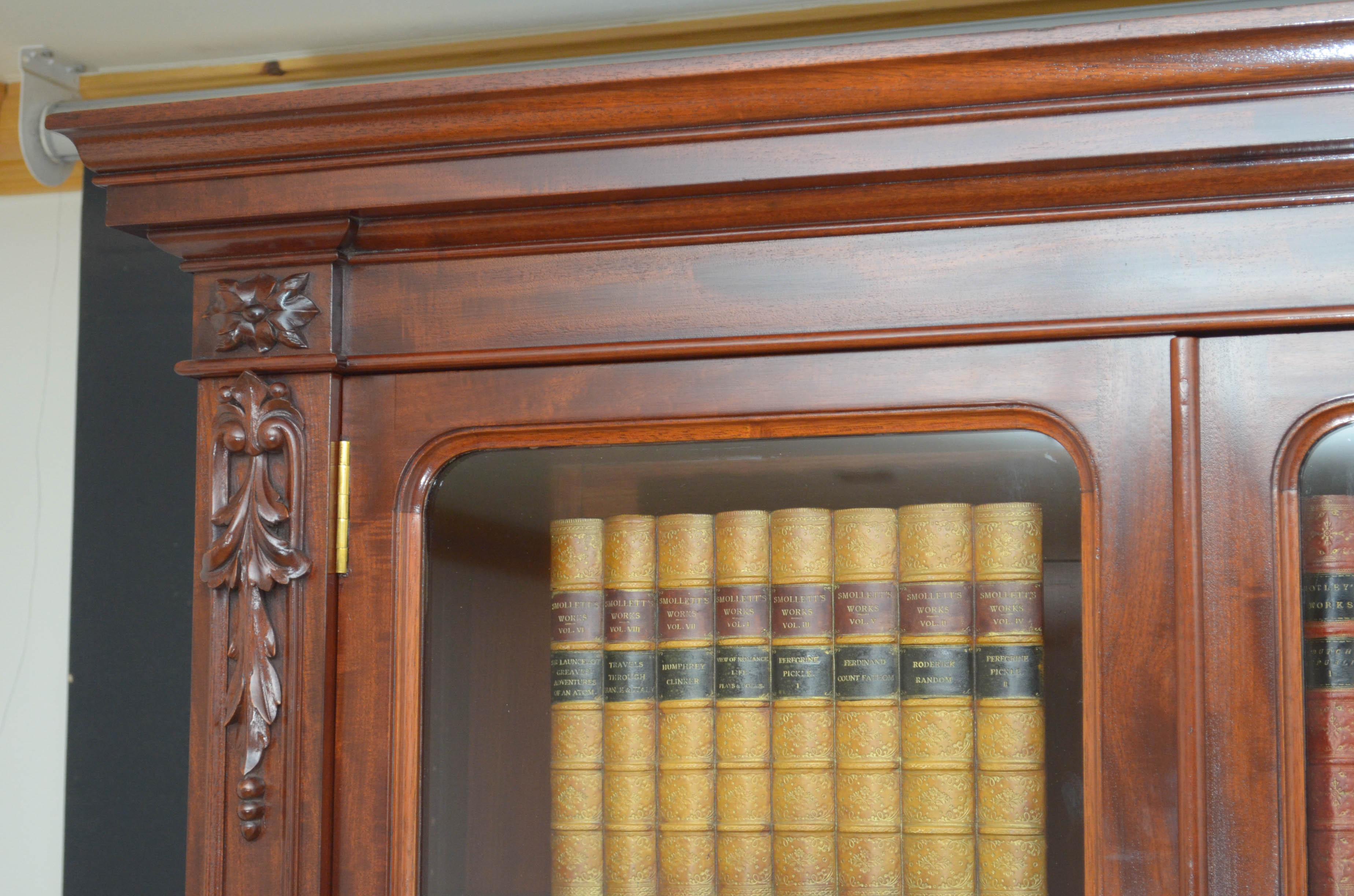Sn4764, fine quality Victorian bookcase in mahogany, having cavetto cornice above 3 glazed doors fitted with original working locks and key and enclosing height adjustable shelves, all flanked floral carvings. The projecting base having 3 figured