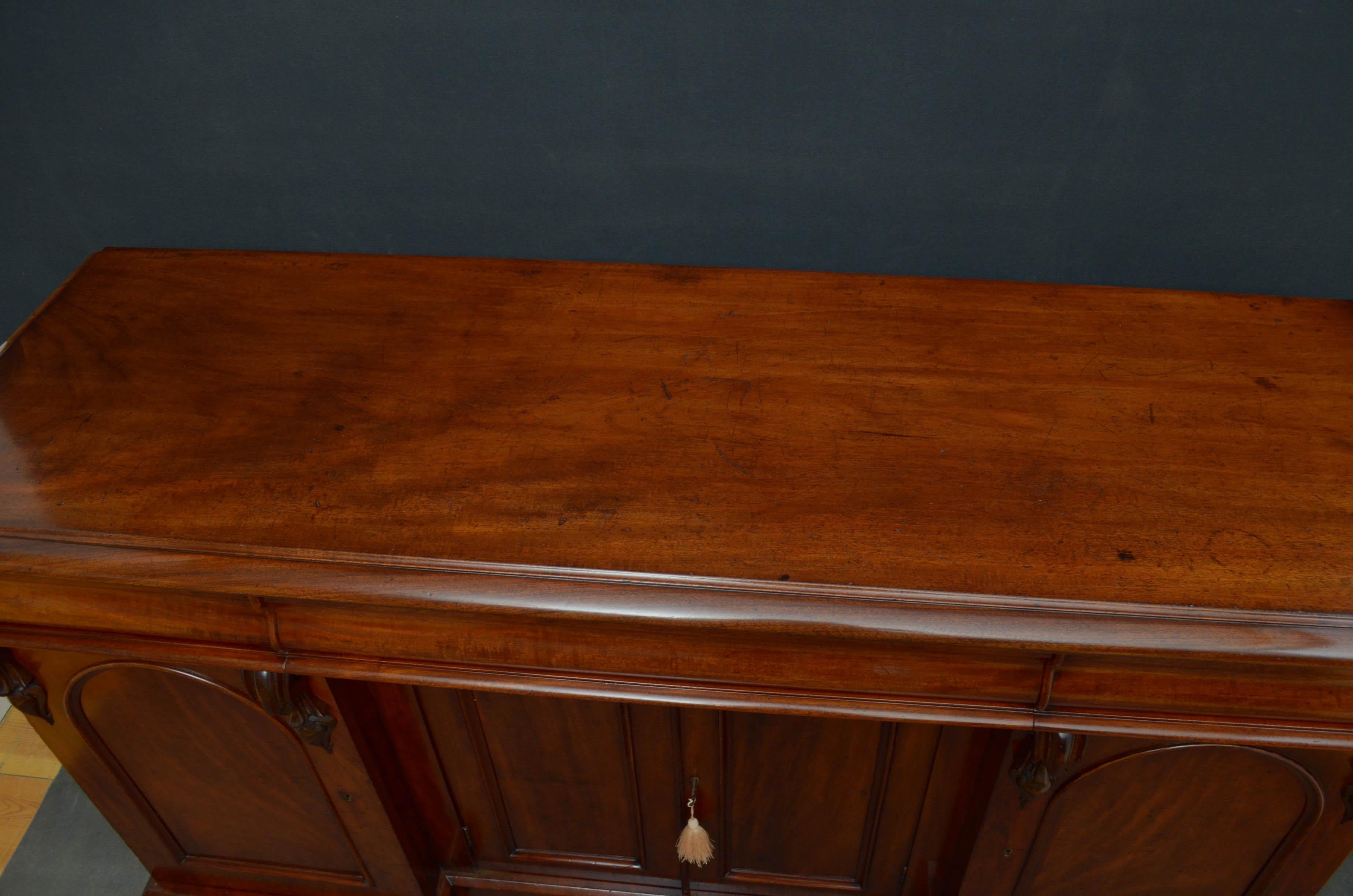 R00 Victorian 4-door sideboard in mahogany, having figured top above 3 shaped, mahogany lined drawers and arched and panelled cupboard doors enclosing a shelf, all flanked by further cabinet doors enclosing sliders and a shelf, all decorated with