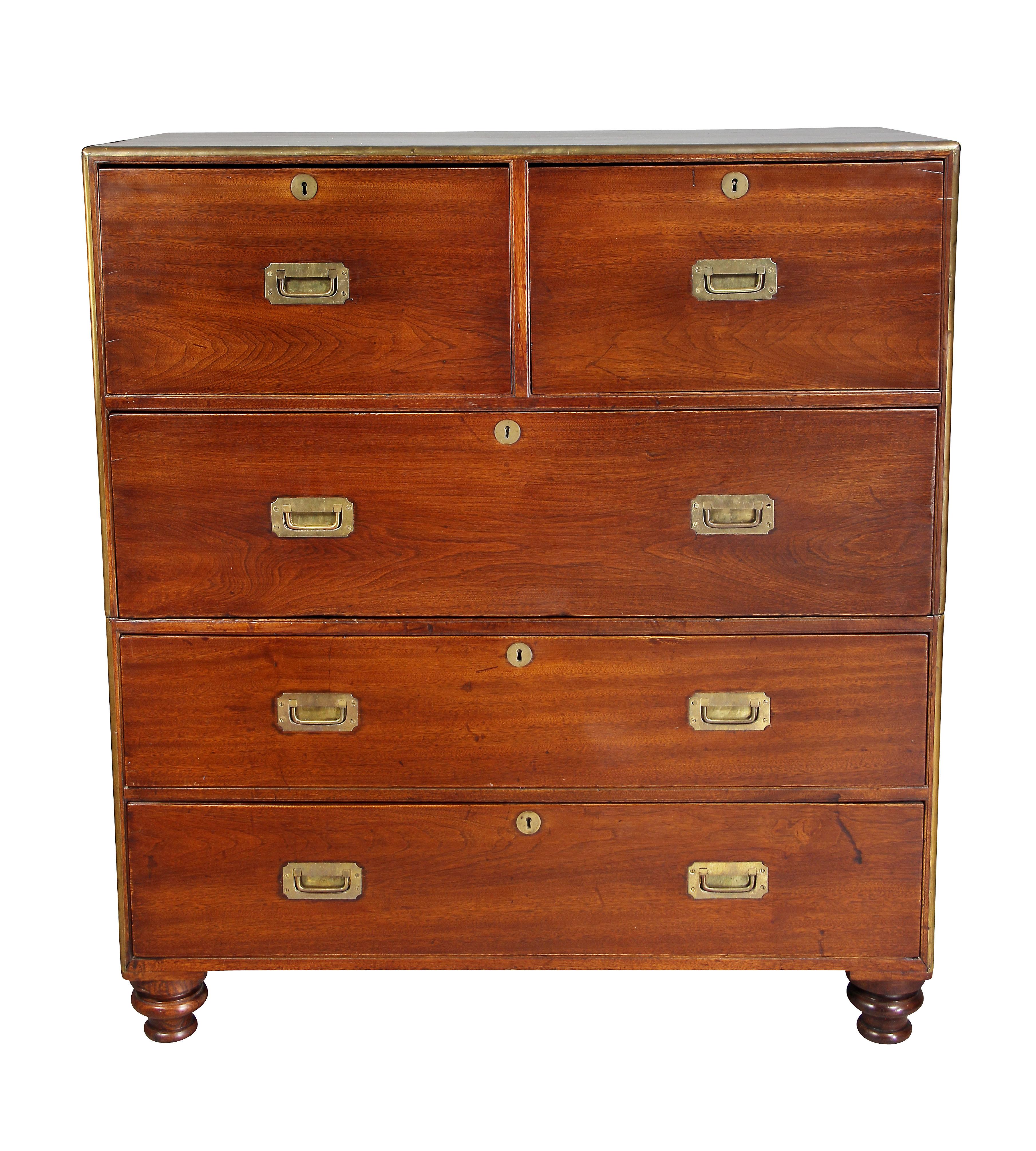 In two sections with rectangular top over two drawers and three long drawers, toupie feet, brass side carrying handles and brass corner trim all around.