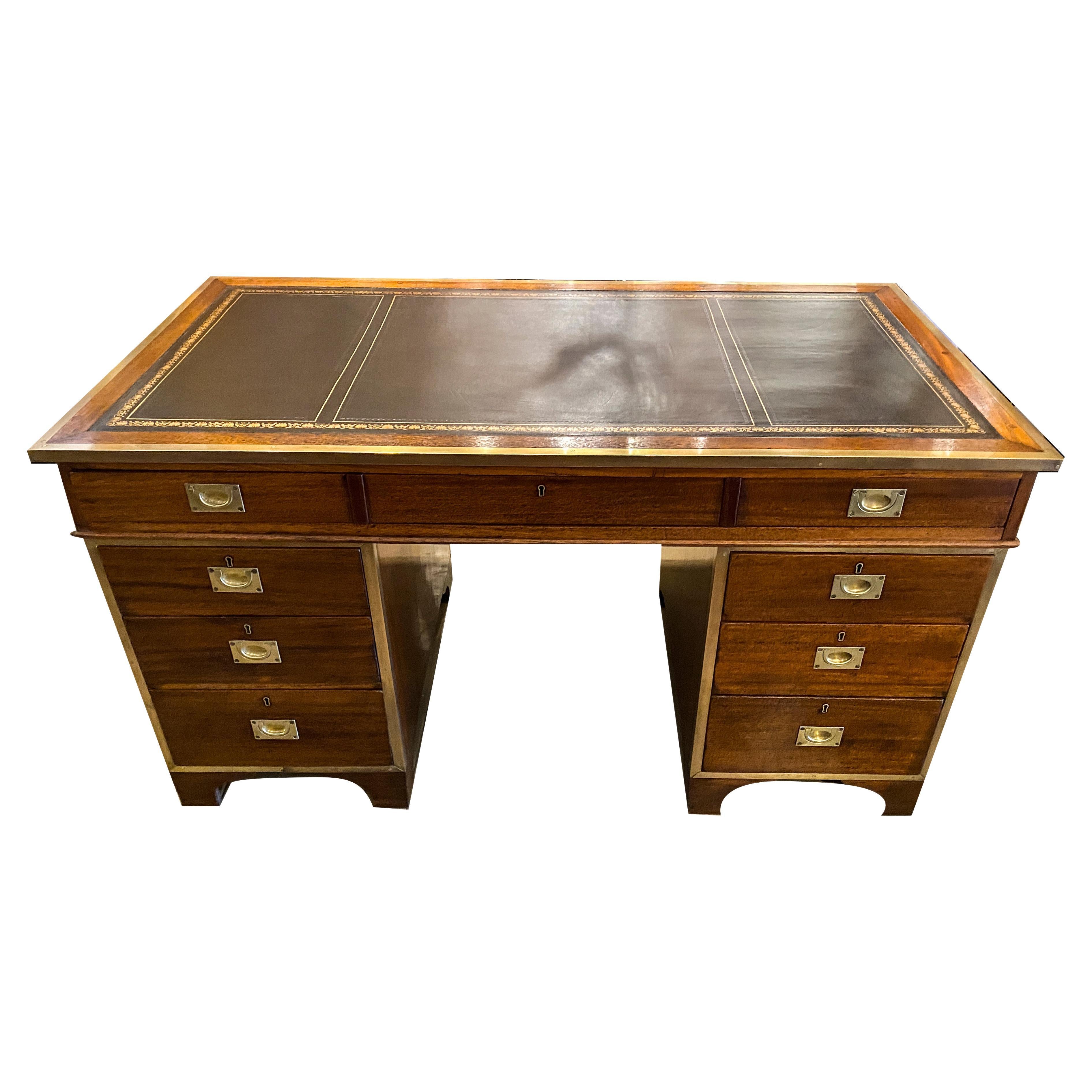 With an inset black leather top within a border over a long drawer, two pedestal base each with three drawers. Bracket feet. All with inset brass handles.