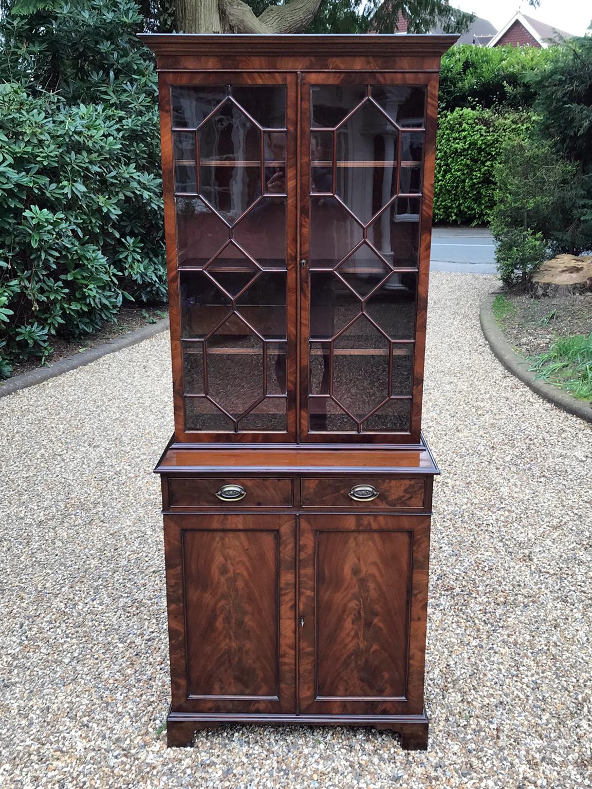 A late Victorian mahogany bookcase or cupboard with two mahogany lined drawers and brass oval handles. Three adjustable shelves to the top bookcase section. The cupboard below has one shelf which can be adjusted. Comes apart in two separate sections