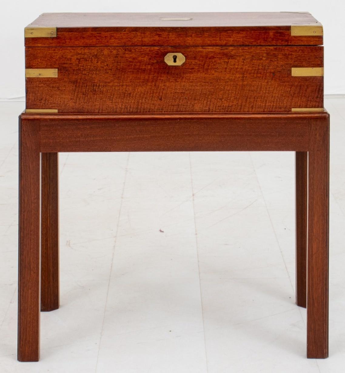 Victorian brass-bound mahogany lap desk or writing box on stand, the box rectangular with central cartouche plate, brass-bound corners, and with two flush hinged handles, opening to reveal a green baize lined surface with ink and paper wells.