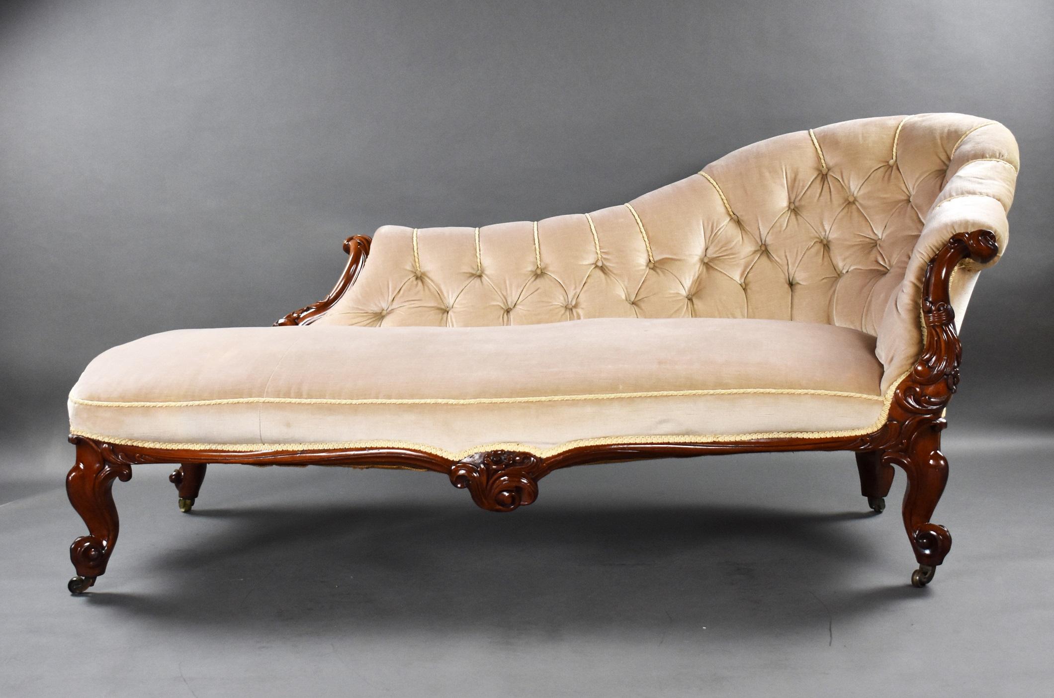 Victorian mahogany chaise lounge upholstered in a buttoned velour, the chaise, the arms and cabriole legs are finely carved with scrolls, raised on brass castors.