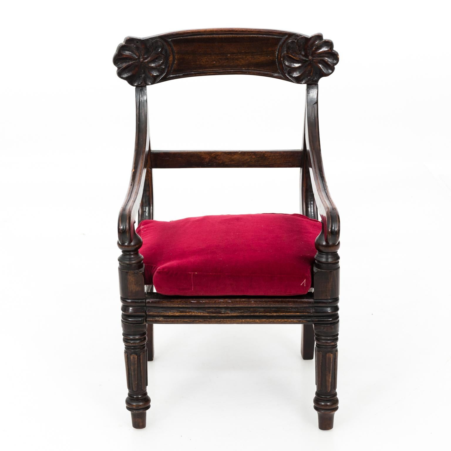 Victorian mahogany child's armchair with shallow relief floral carvings on the top rail and a red velvet upholstered seat, circa turn of the century.
  