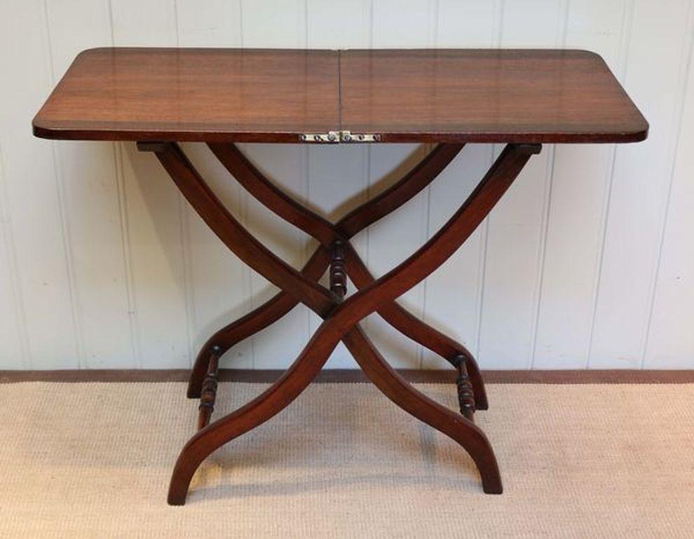 Victorian mahogany coaching table comprising of a folding top in two halves with a revolving locking bar underneath supported by a collapsible X-frame. The leg supports are united by three turned stretchers.