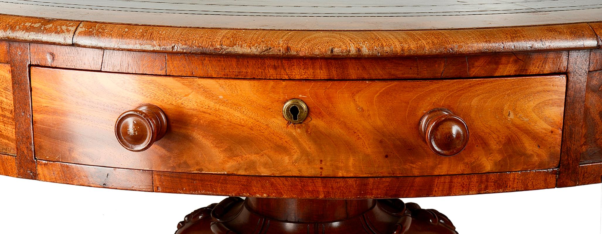 A very good quality Victorian period Mahogany drum table, having an inset leather top, four oak lined frieze drawers and four dummy, each with turned Mahogany handles, raised on a tapering column pedestal, carved scroll decoration and three splay