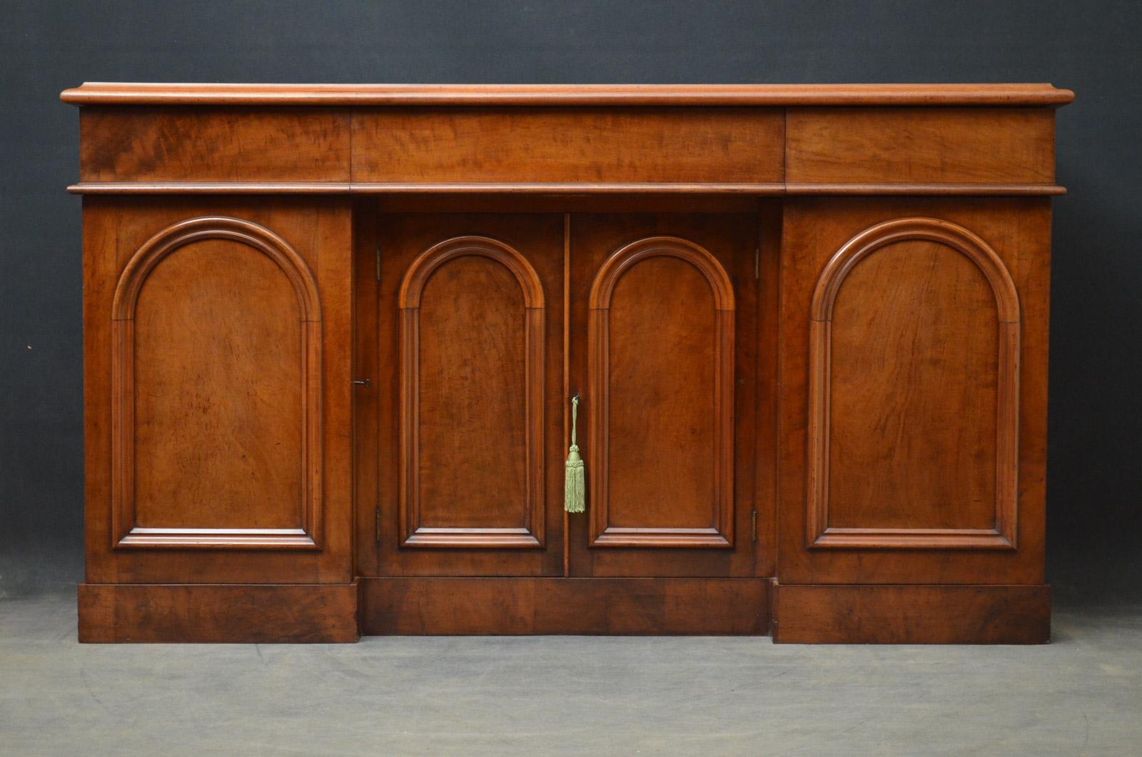 K0337, fine quality Victorian mahogany sideboard of soft and mellow color, having figured mahogany, moulded top above three mahogany lined drawers and a pair of recessed, arched and panelled figured mahogany cupboard doors enclosing shelf, flanked