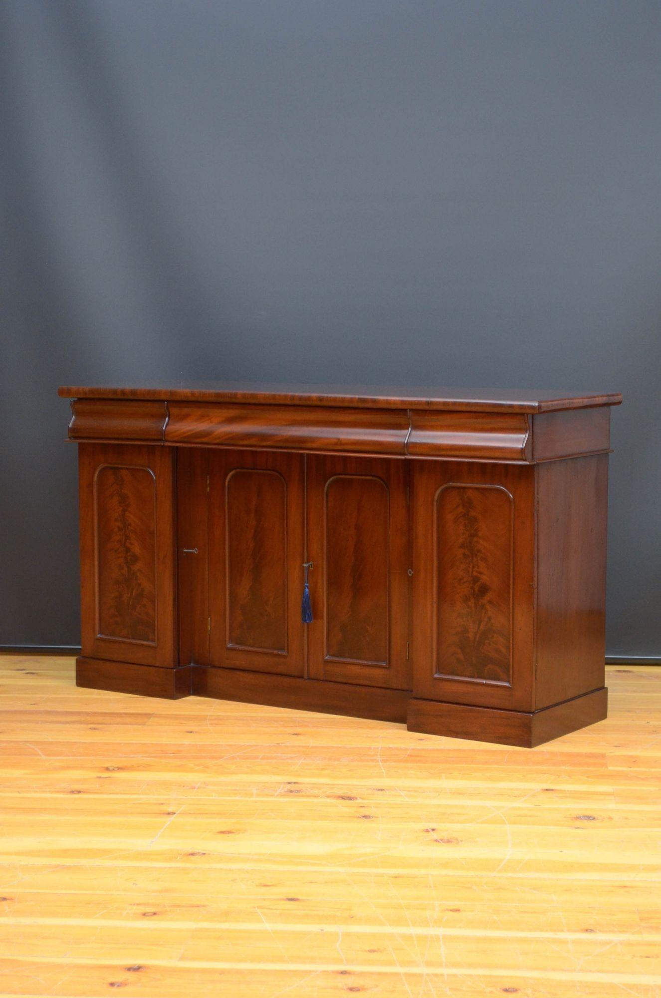 J026 Fine quality Victorian mahogany, inverted break front sideboard, having figured mahogany top above three flamed mahogany concave drawers and a pair of flamed mahogany arched cabinet door fitted with working lock and a key and enclosing two