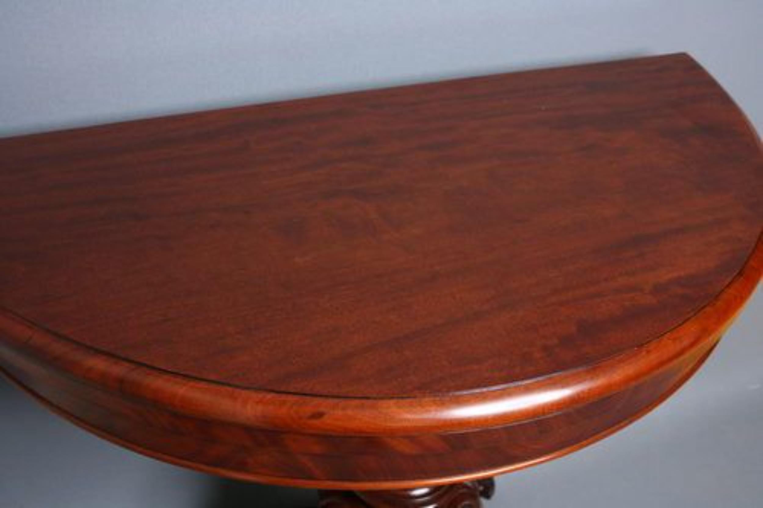 Sn1095 fine quality Victorian half moon mahogany games table with moulded border to top, raised upon turned centre pedestal with carved ovals, quadruple leaf carved down swept supports, terminating in scrolling leafy toes with castors. All in