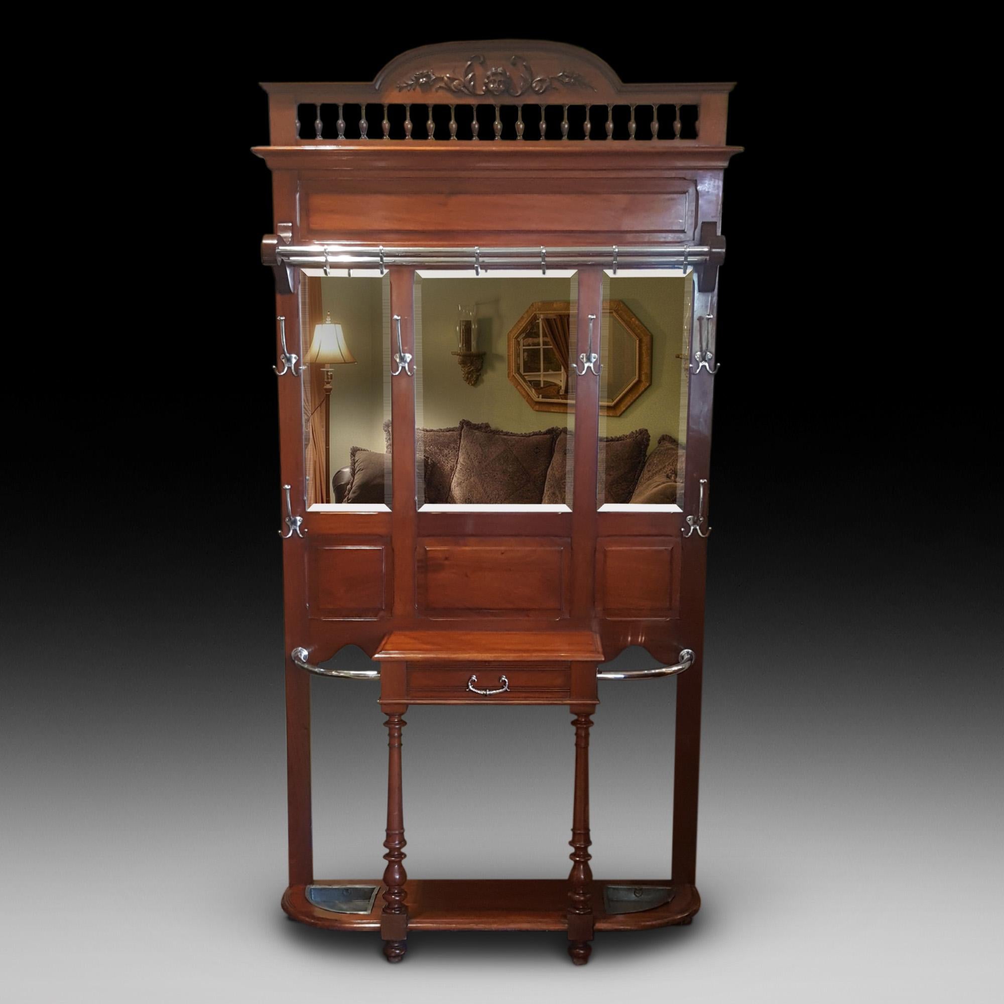 Victorian mahogany hall stand with carved pediment, steel hooks and handle, 3 double beveled mirrors above an oak lined drawer and tin drip trays.
Measures: 48